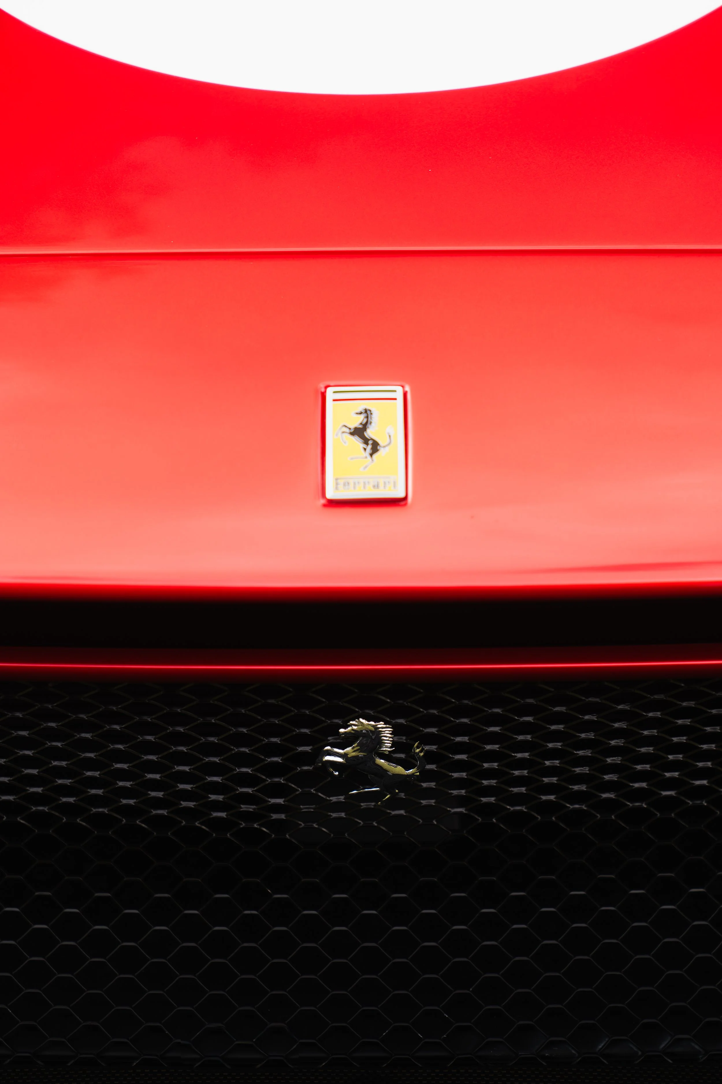 Close-up of a red Ferrari car with a prancing horse emblem on the grille.