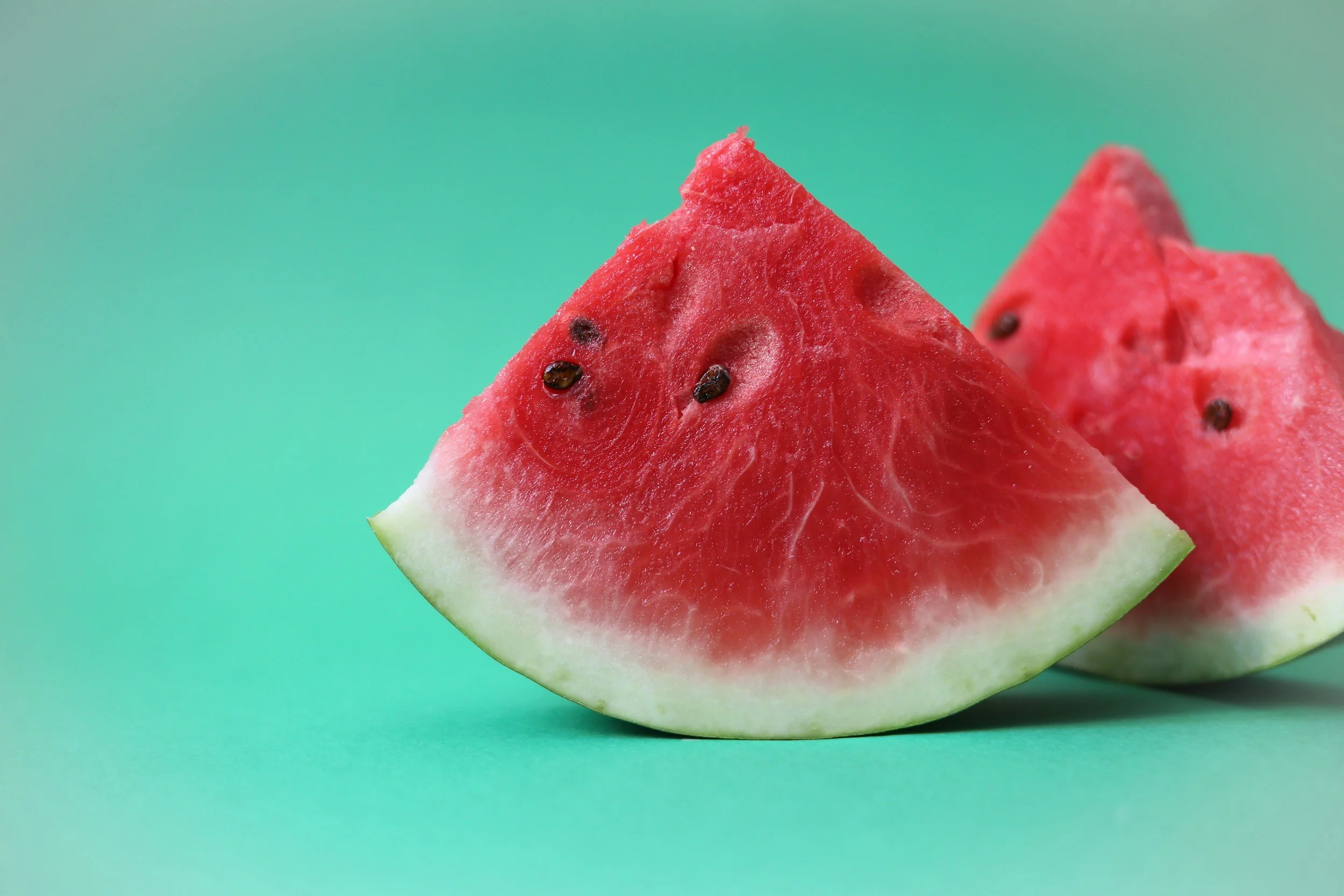 A close-up of a sliced watermelon on a green background.