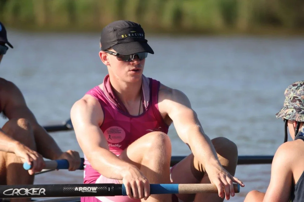 A man giving a thumbs-up in a workshop or lab with electrical equipment, wires, and tools on a table and a green cabinet with tools in the background.