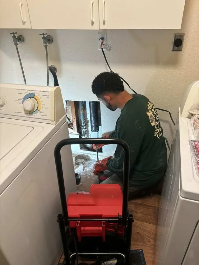 Technician operating a snake to clear drain blockage
