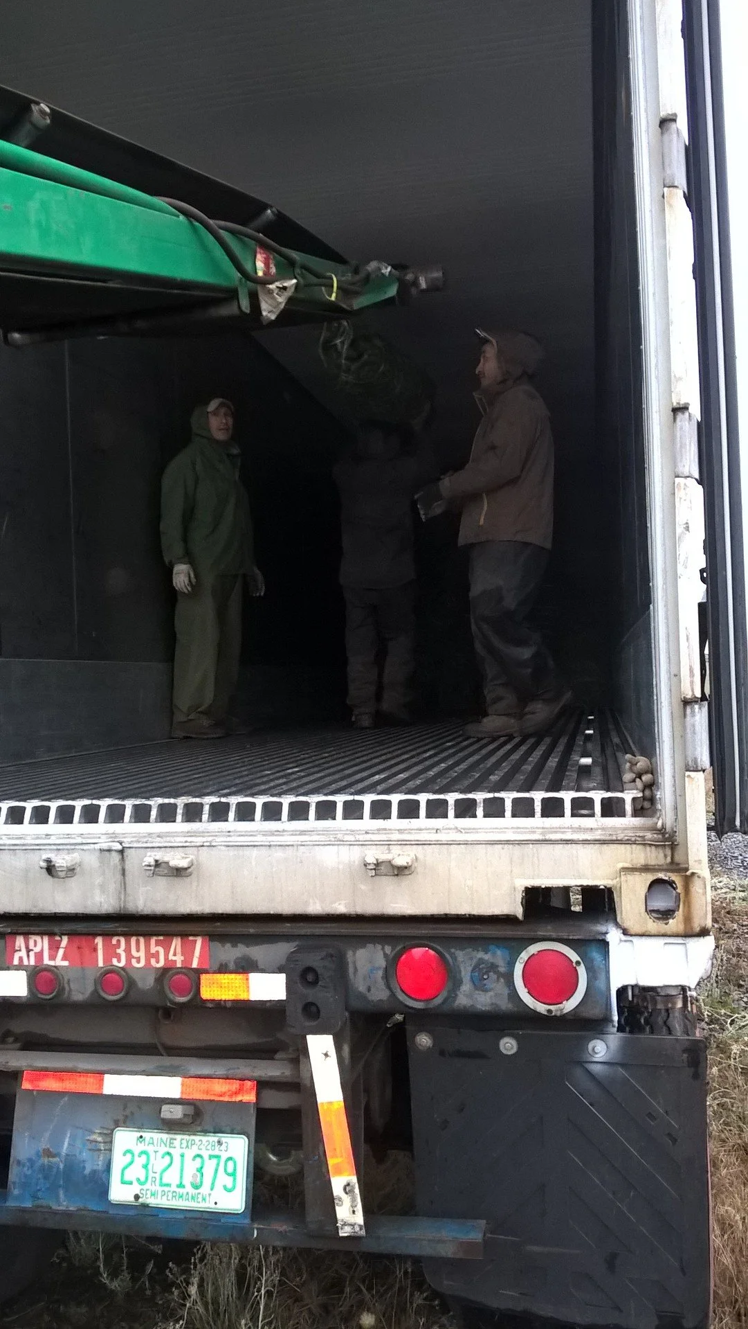 People working inside a large truck with an open back door, preparing equipment or cargo.