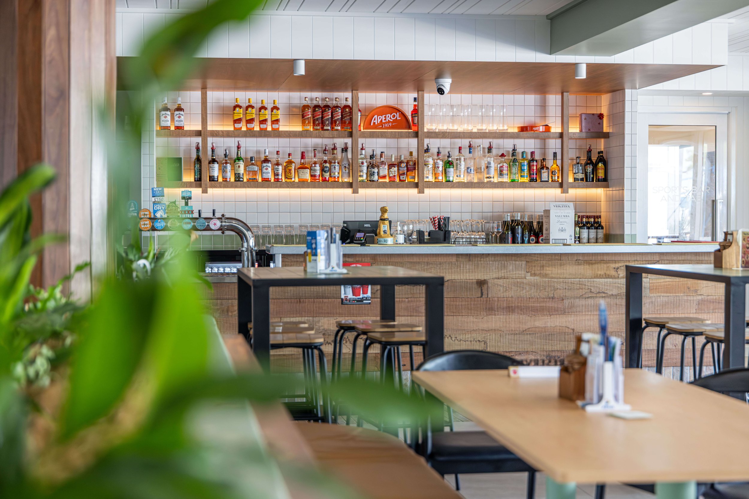 Modern bar and dining area with shelves of liquor bottles and glasses in The Fairfield.