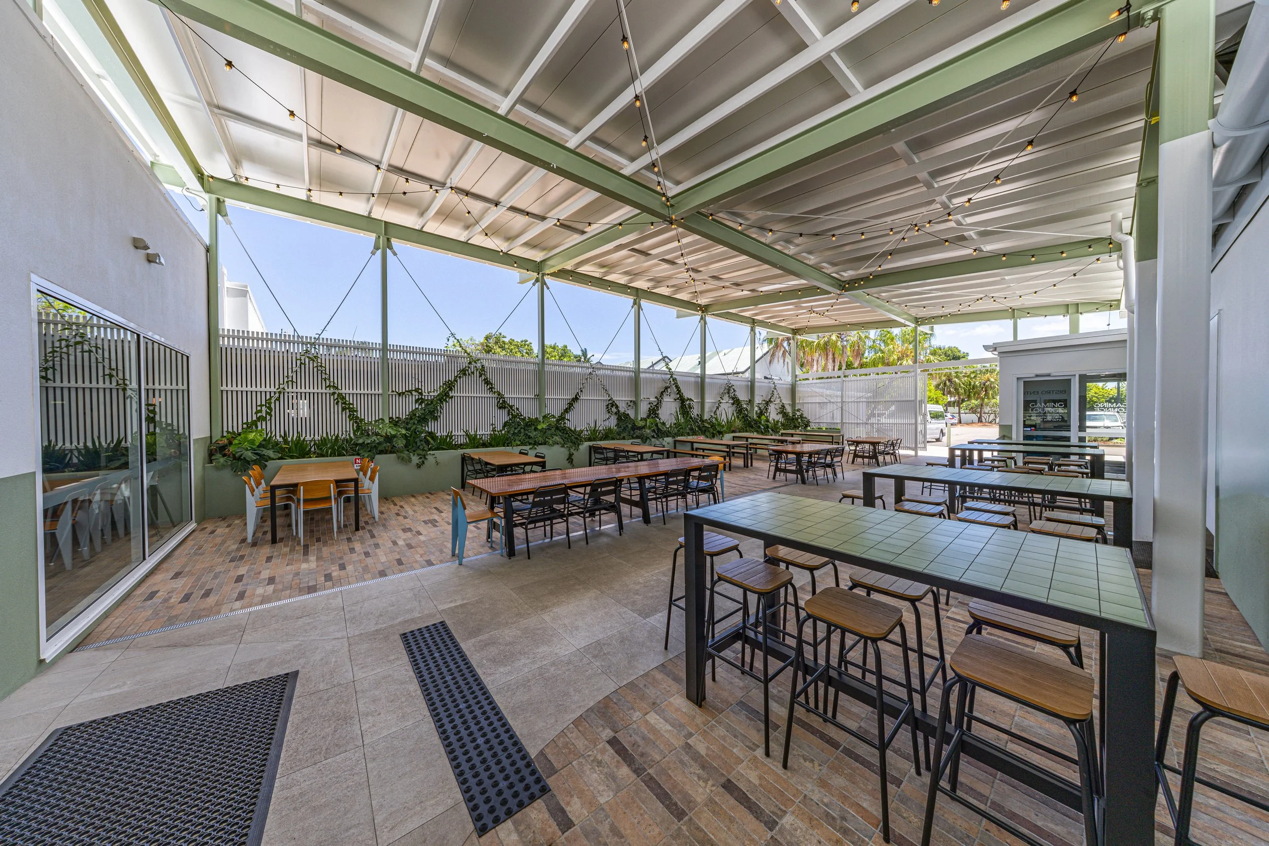 Outdoor tables in a beer garden with strings of lights on the ceiling.