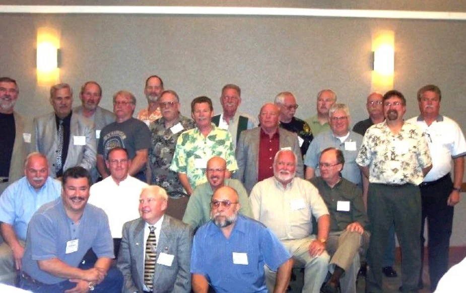 Group of men and women gathered in a conference room, posing for a photo.