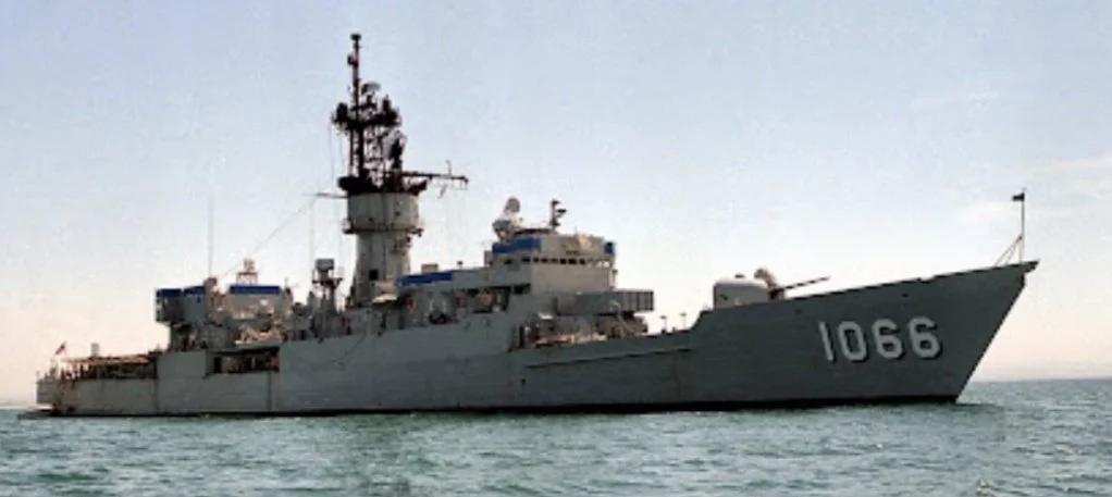 Military ship with the number 1066 on its hull sailing on the ocean under a clear sky.