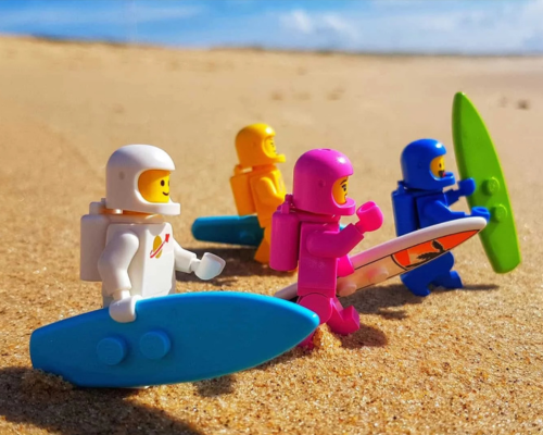 An elderly woman is supported by a man while walking outdoors with a walking stick.