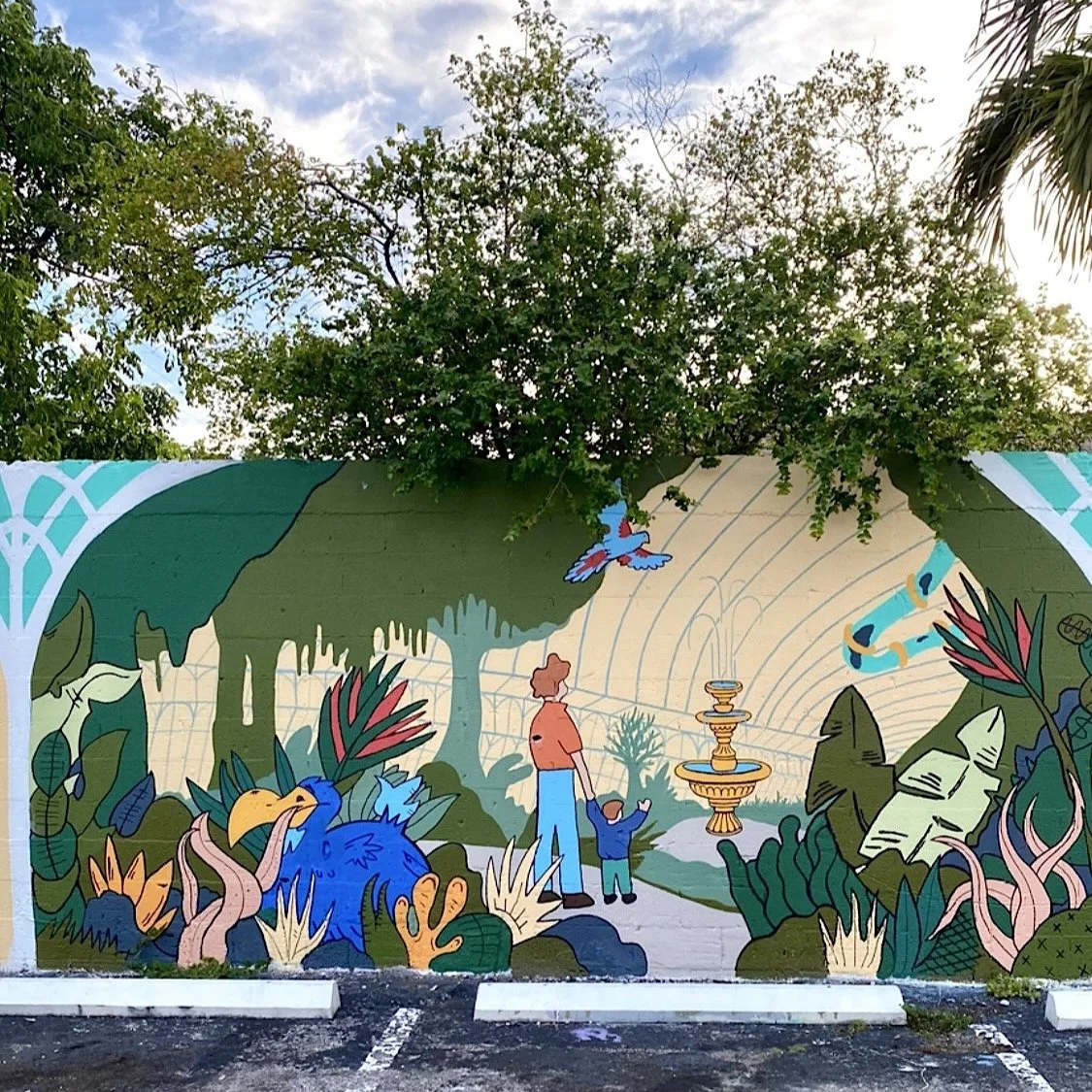 Colorful wall mural with a water fountain, a father and son, a big blue bird surrounded by foliage.