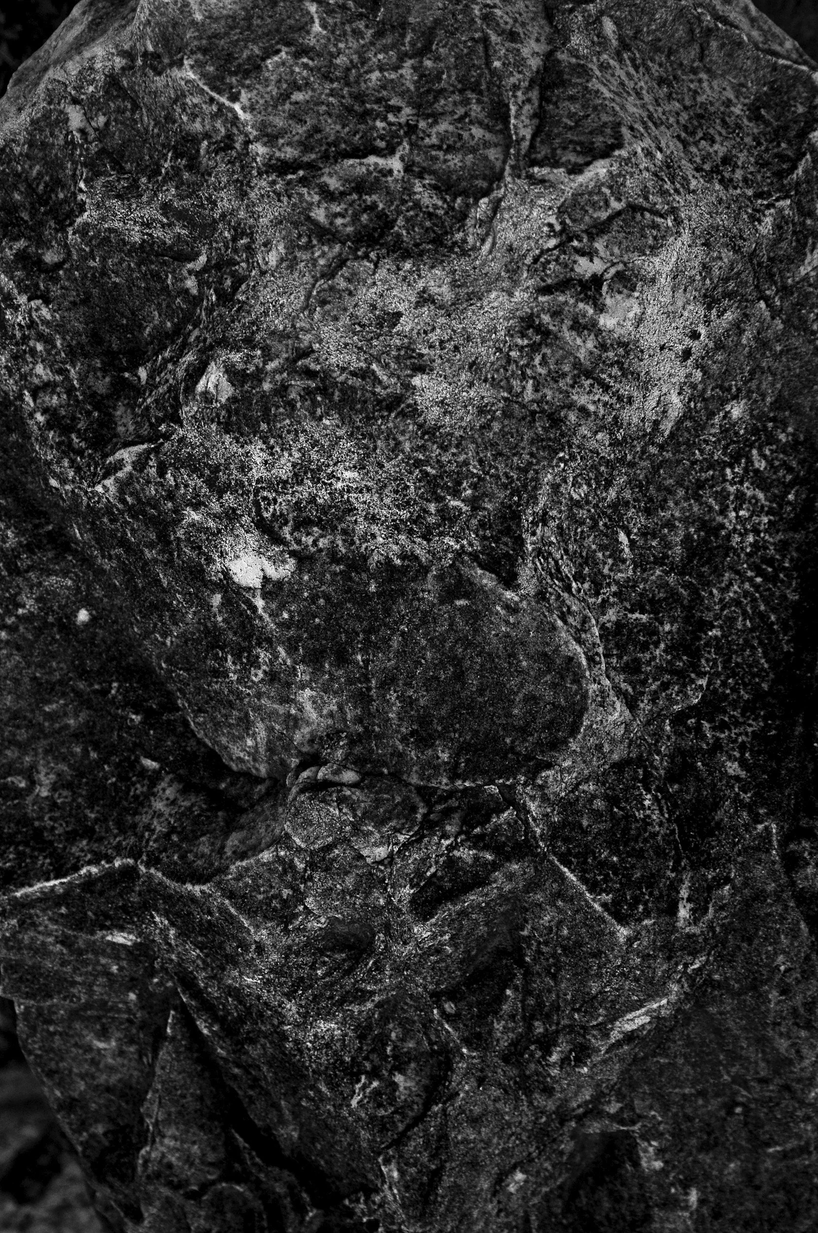 Close-up black and white image of textured rocks and stones with various shapes and rough surfaces.
