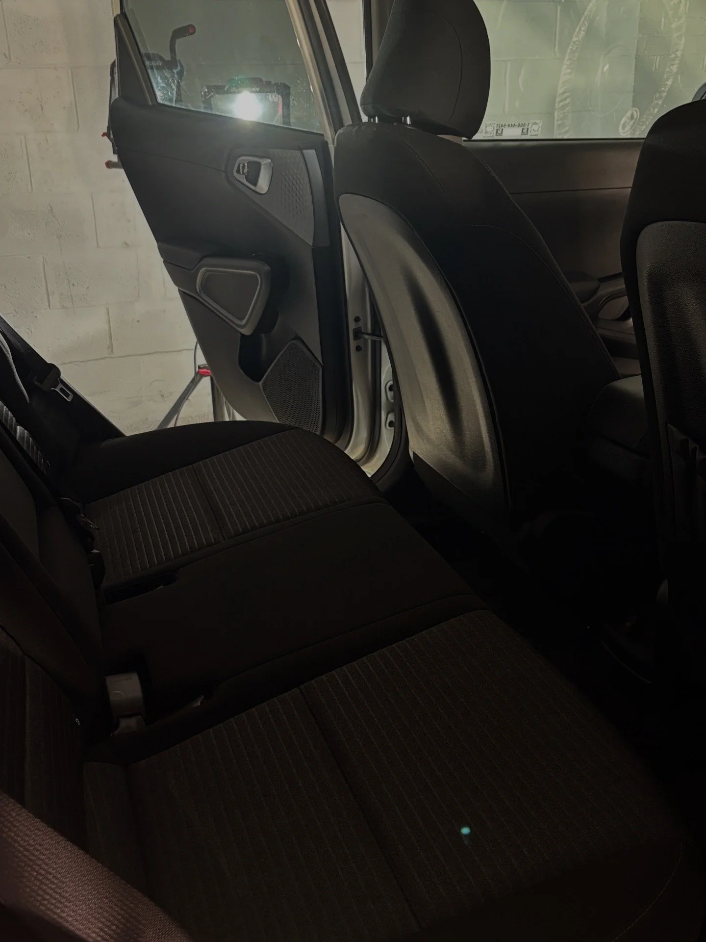 The backseat area of a car, showing the rear seats and the open rear door.
