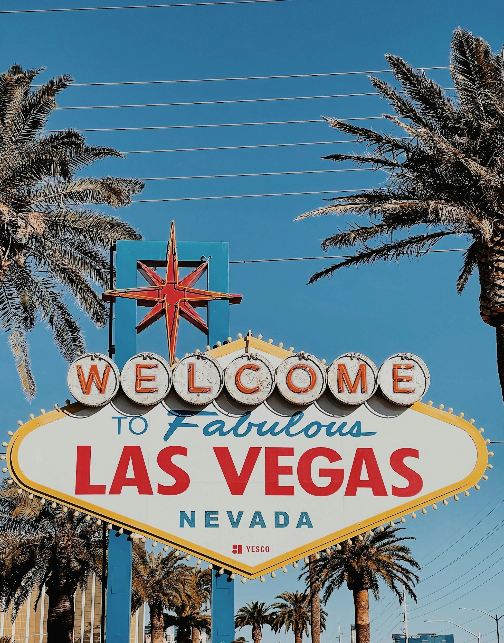 The iconic Las Vegas welcome sign with the words 'Welcome to Fabulous Las Vegas Nevada,' surrounded by palm trees and a clear blue sky.