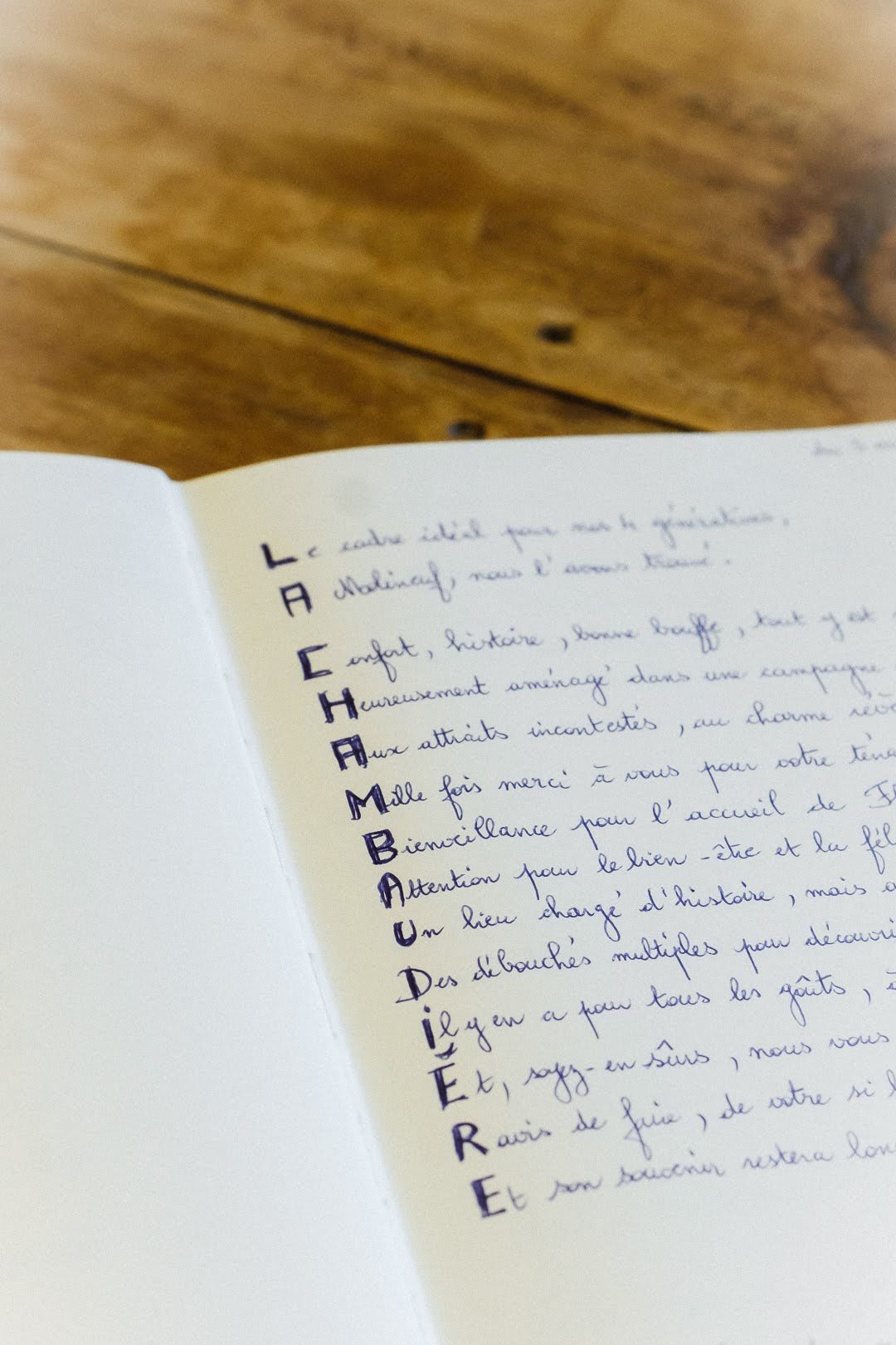 Page d'un carnet avec un poème manuscrit en français, où chaque ligne commence par une lettre de l'alphabet mise en évidence en vertical.
