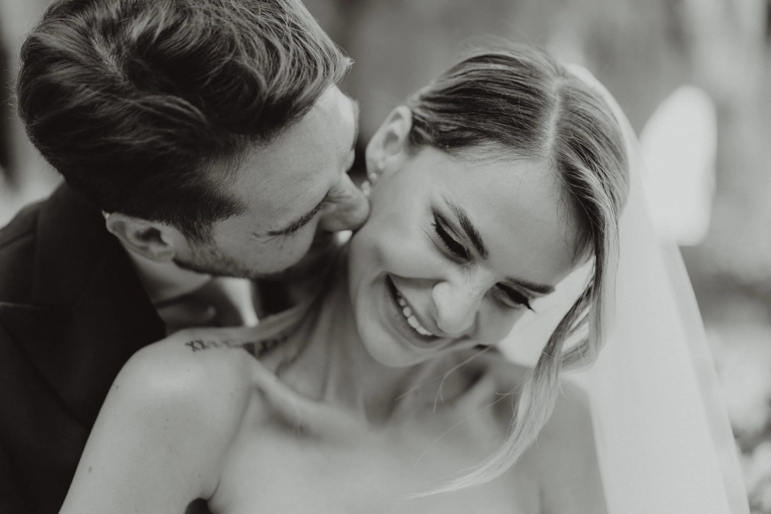 Una coppia sorridente, un uomo e una donna, vicino e affettuosi, in un momento di intimità, in bianco e nero.