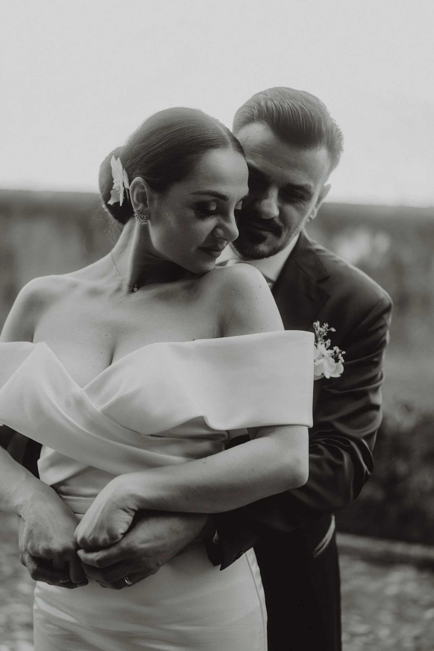 Una coppia di sposi in abiti da matrimonio abbracciati, in un ritratto in bianco e nero.