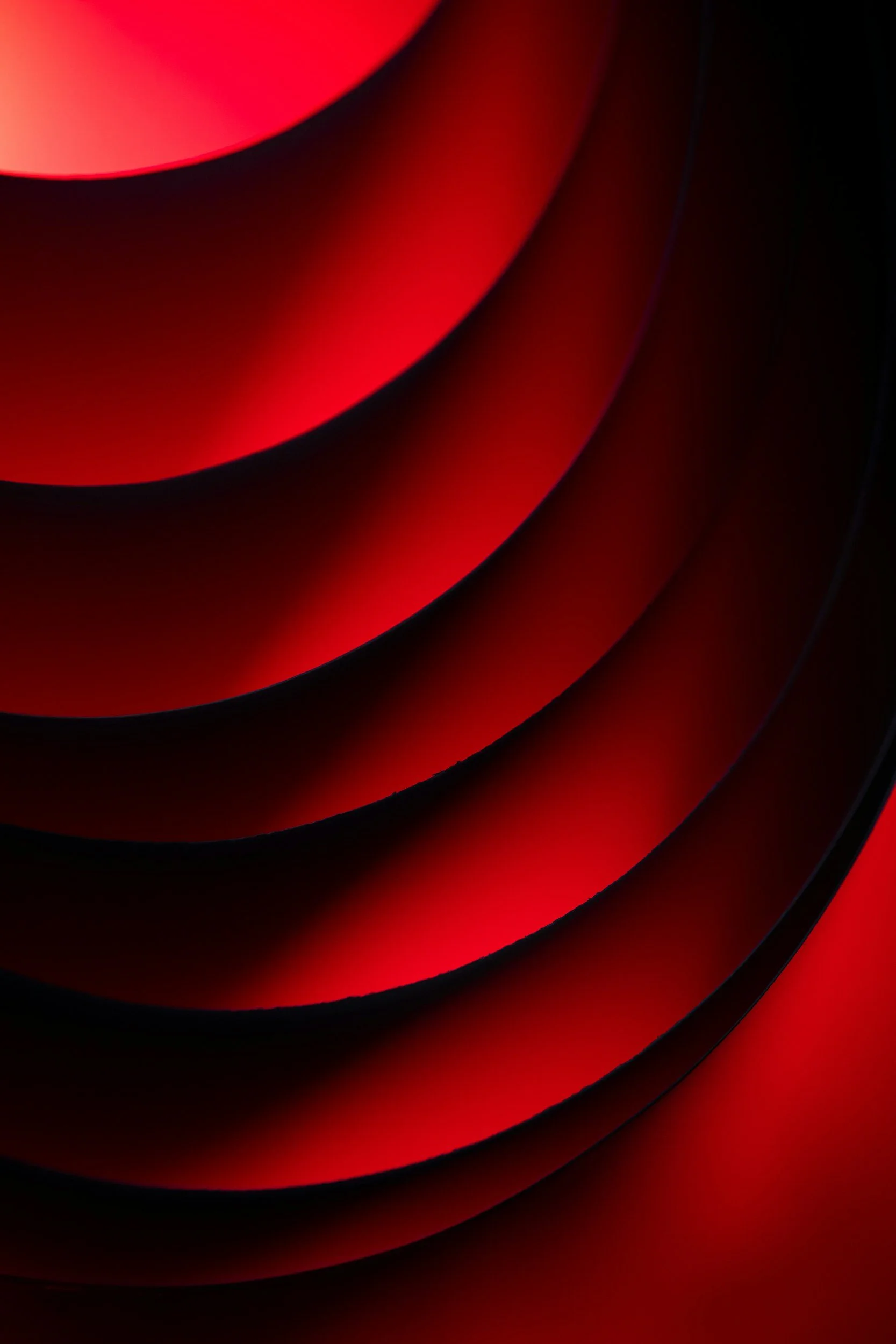 Close-up of a spiral staircase with red and black colors, highlighting the curved edges and shadows.