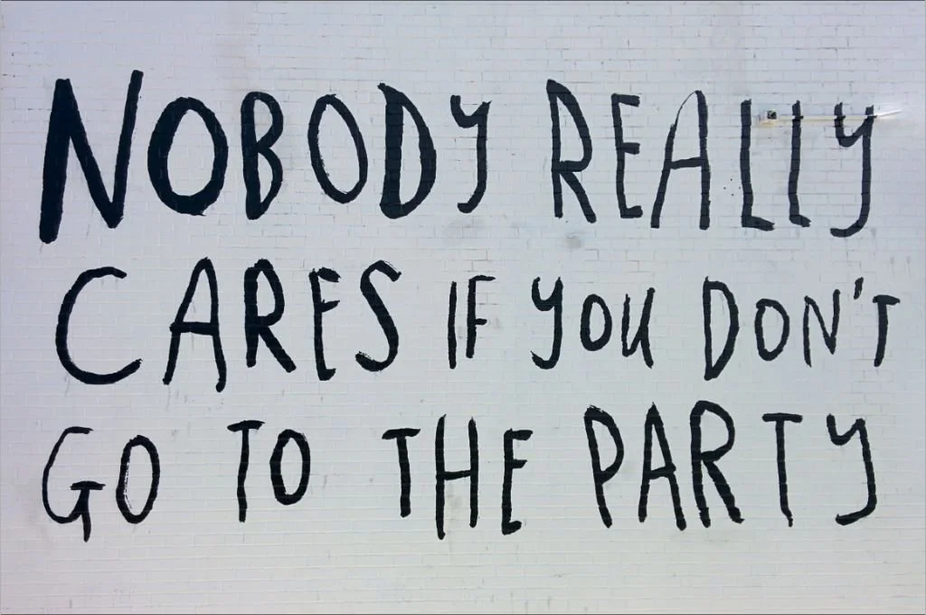 Schwarzer Schriftzug auf einer weißen Wand: Nobody really cares if you don't go the the party