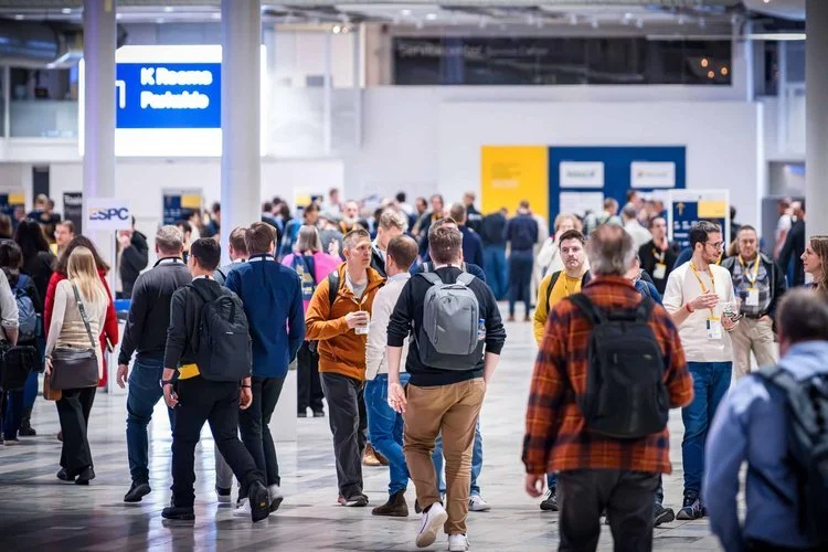 Conference delegates networking on a busy exhibition floor captured by a professional event photographer.