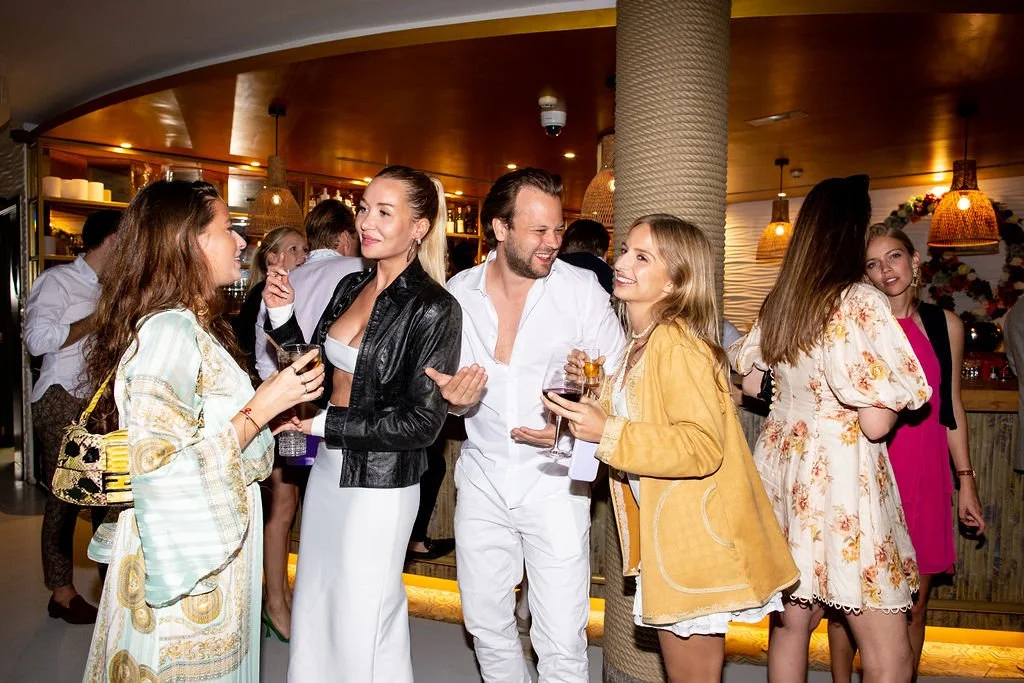 Guests socialising and drinking at a lively indoor event in London with warm lighting and candid interactions