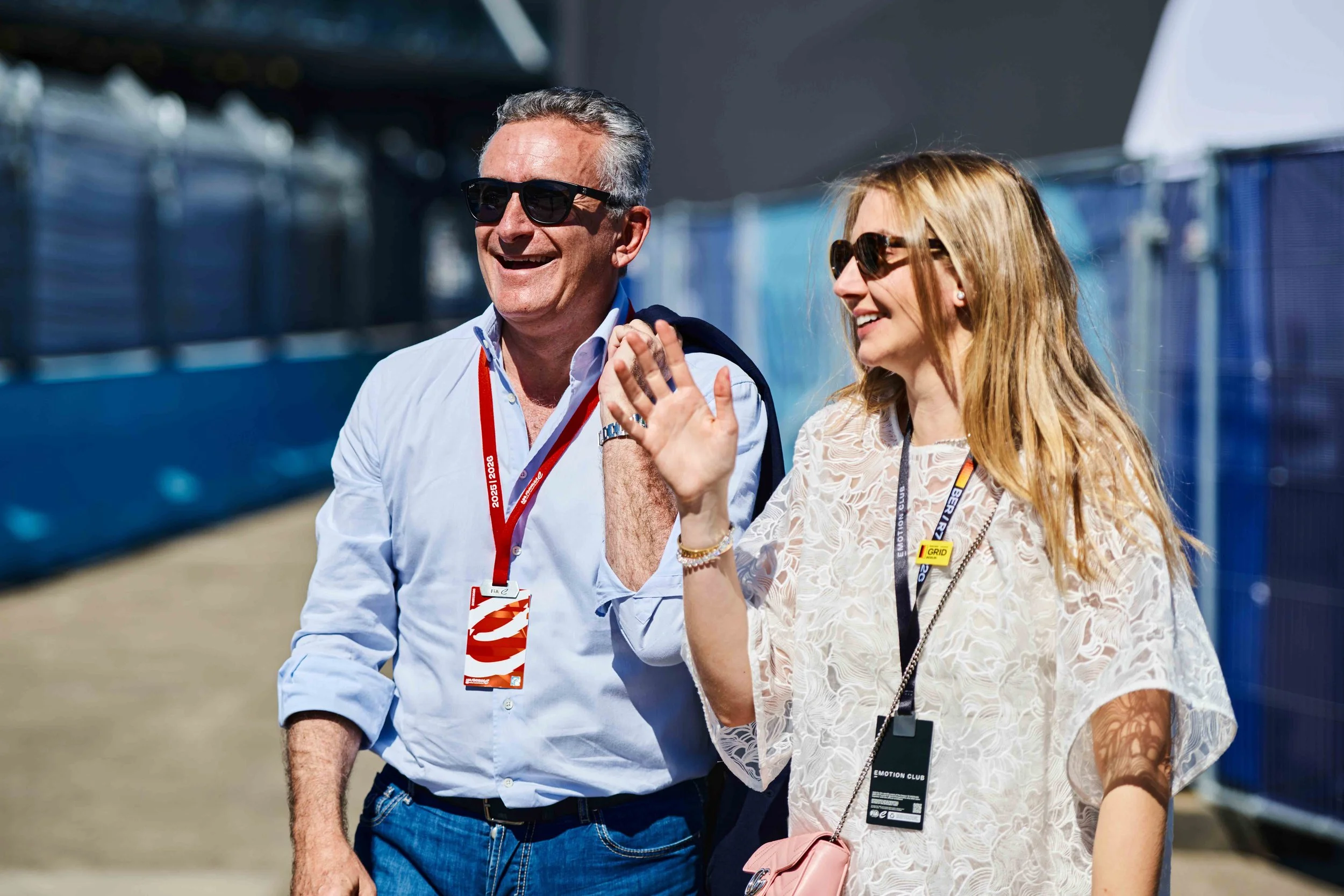 Two attendees wearing event passes walking outdoors and smiling during a corporate event.