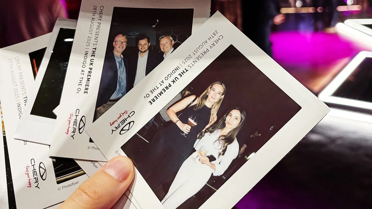 Hand holding Chery-branded instant photo prints of guests at the UK premiere at indigo at The O2, London.