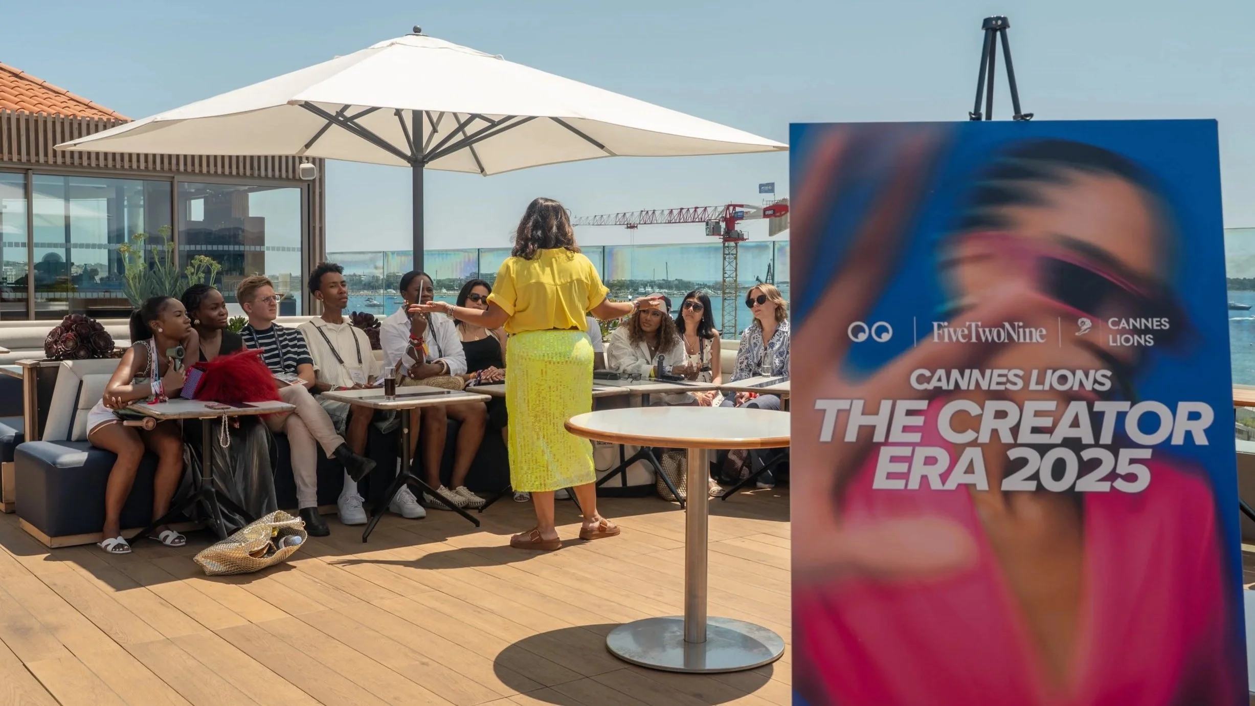 Speaker in yellow addressing seated guests on a rooftop terrace beside The Creator Era 2025 signage during Billion Dollar Boy’s Cannes Lions event.