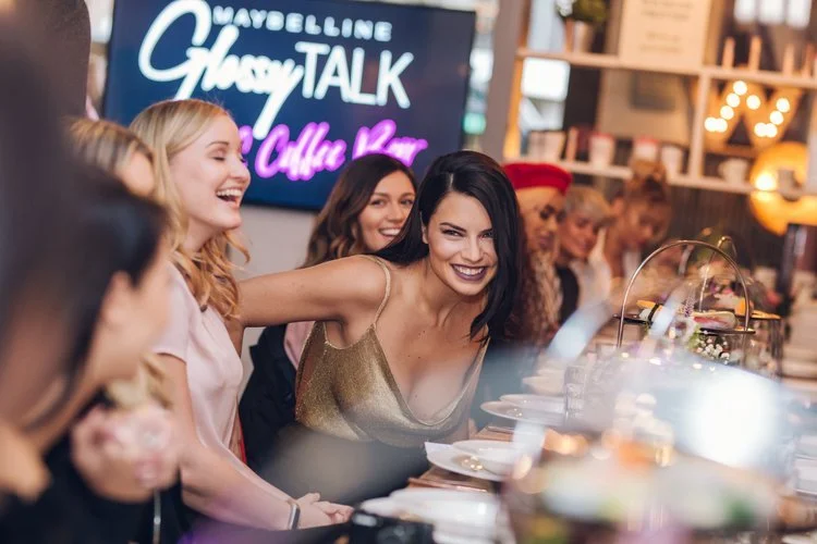 Guests interacting and taking photographs during a branded beauty event inside a retail venue.