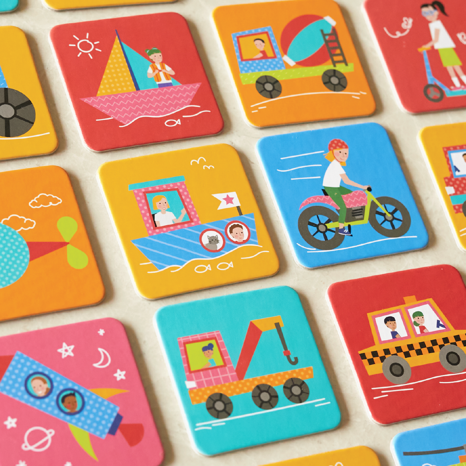 Colorful illustrated tiles showing various scenes: a girl sailing a pink sailboat, a girl in a houseboat, a girl riding a pink bicycle, and a yellow construction vehicle, among others.