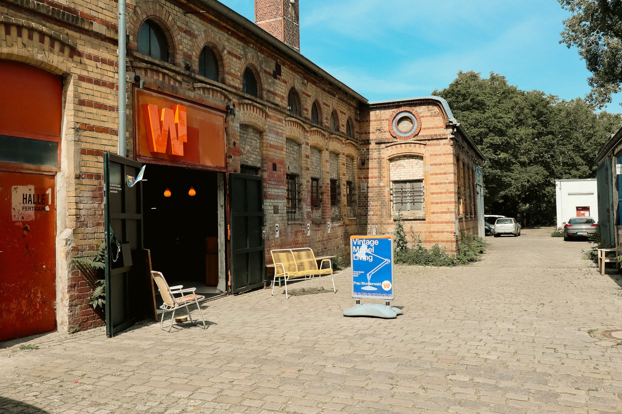 Ein sinstöckiges Backsteingebäude. Über der Tür hängt ein orangenes W.