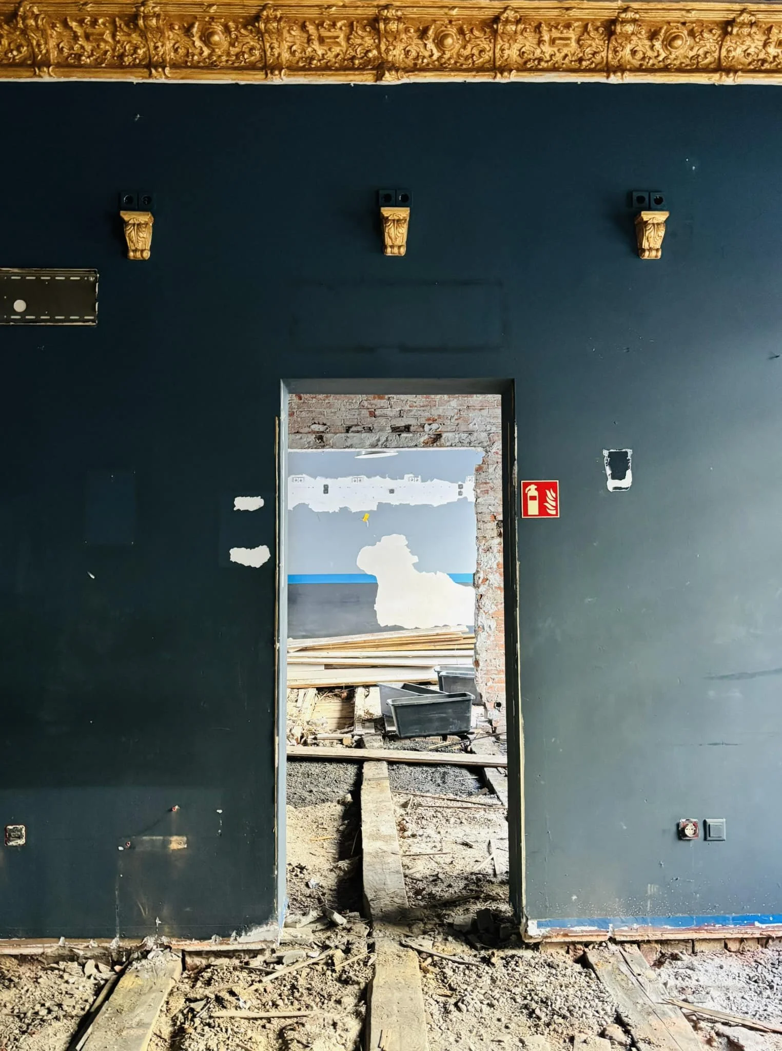 Eine dunkelbalue wand mit Türöffnung. Dahinter Baustelle.