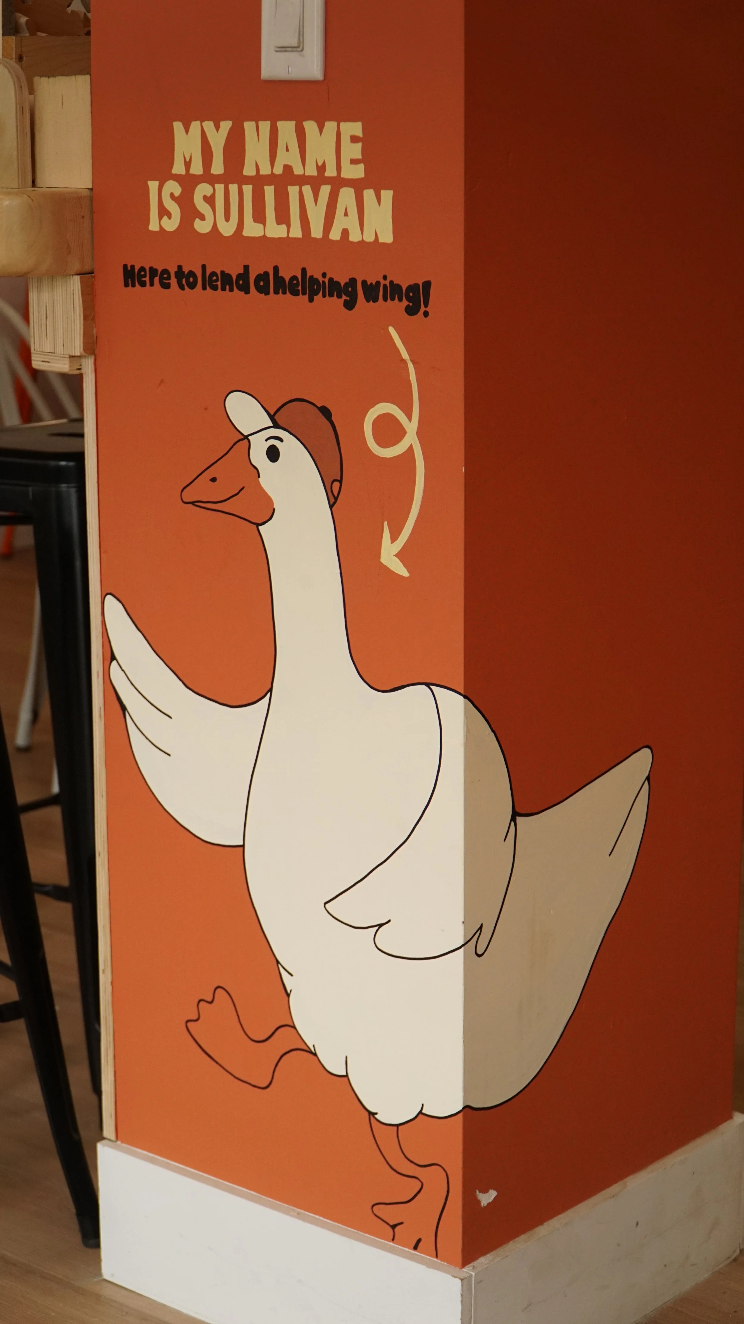 Illustration of a smiling duck wearing a hat, with a speech bubble saying 'My Name is Sullivan' and 'Here to lend a helping wing!' on an orange background.