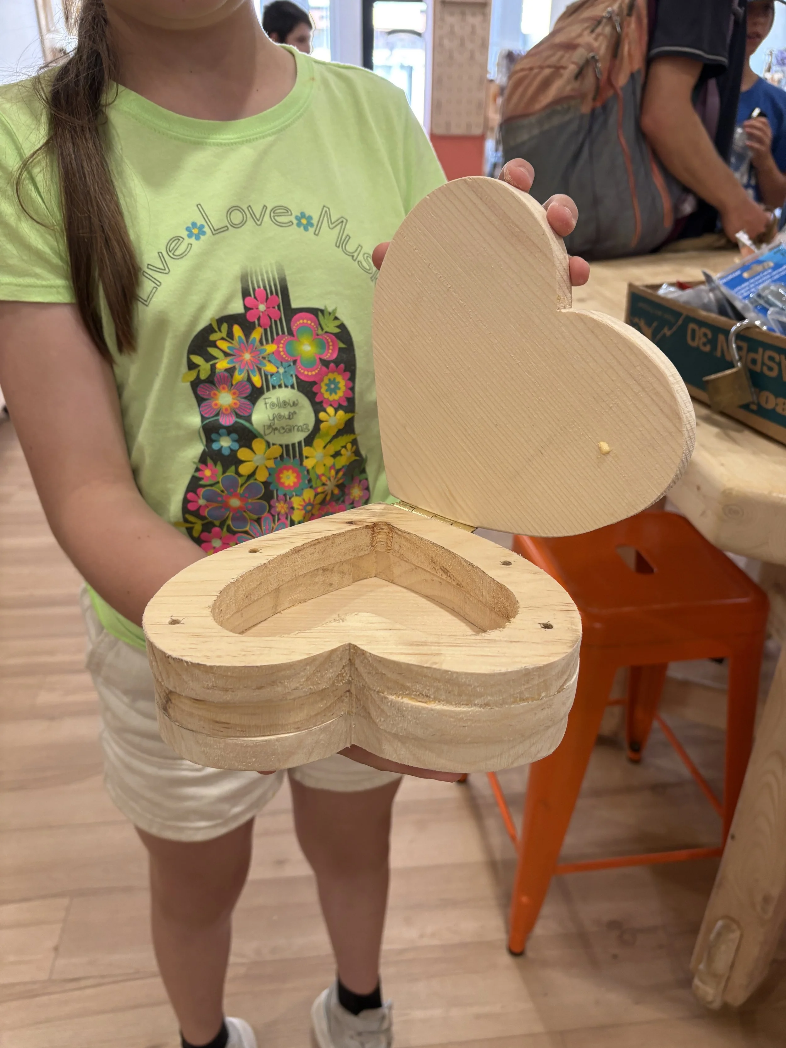 A kid holding a heart shaped box they made from wood