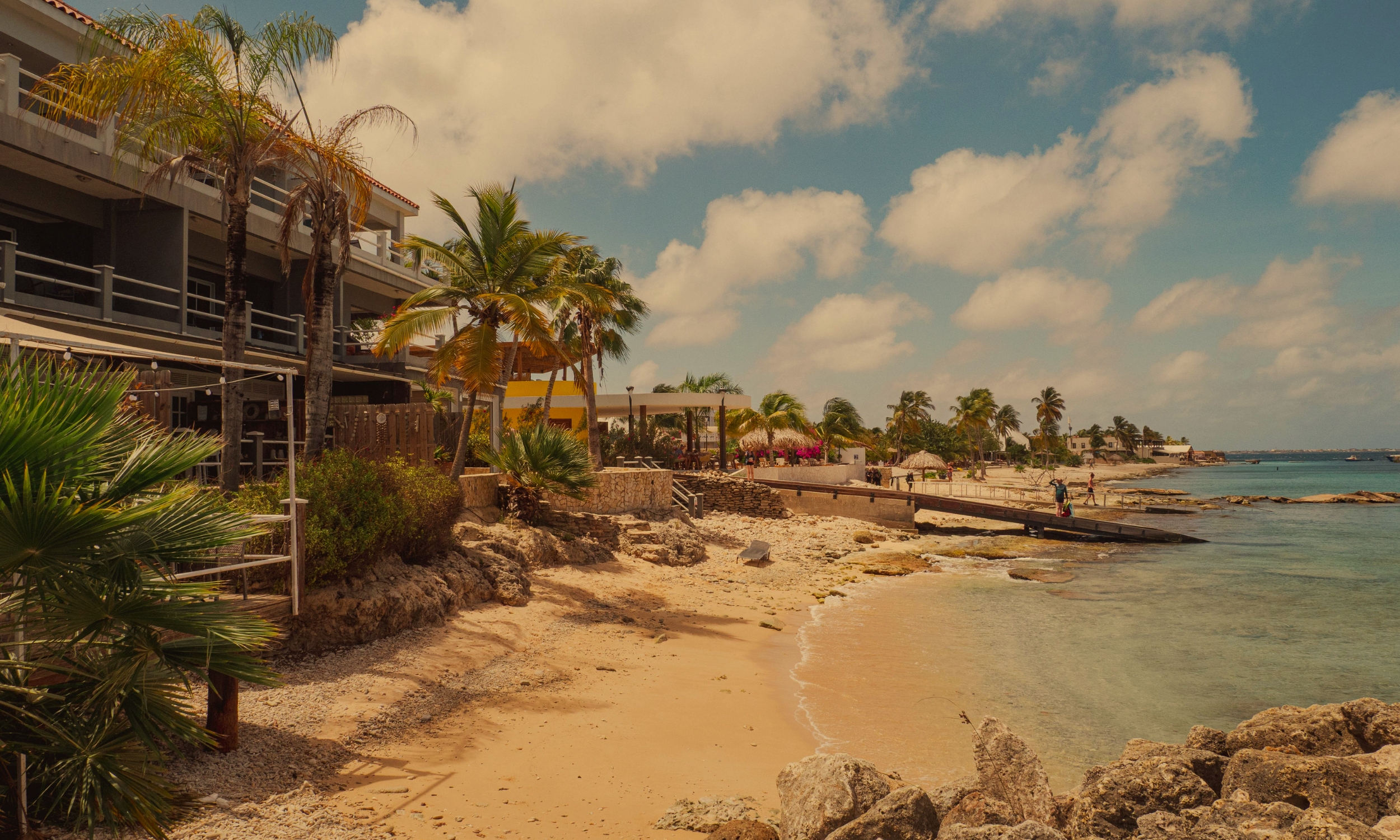 Sandy, arid beach front with a dock and house in Aruba