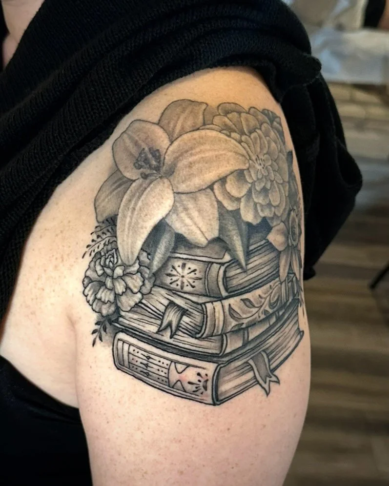 Bookish tattoo done by adding a stack of books underneath Brooke&rsquo;s healed flowers up top, creating a whole bouquet. Bookuet? Anyway, appointments and walk-ins available Wed-Sunday 12-7 PM. DM artists directly or shoot us a text for more info! 7