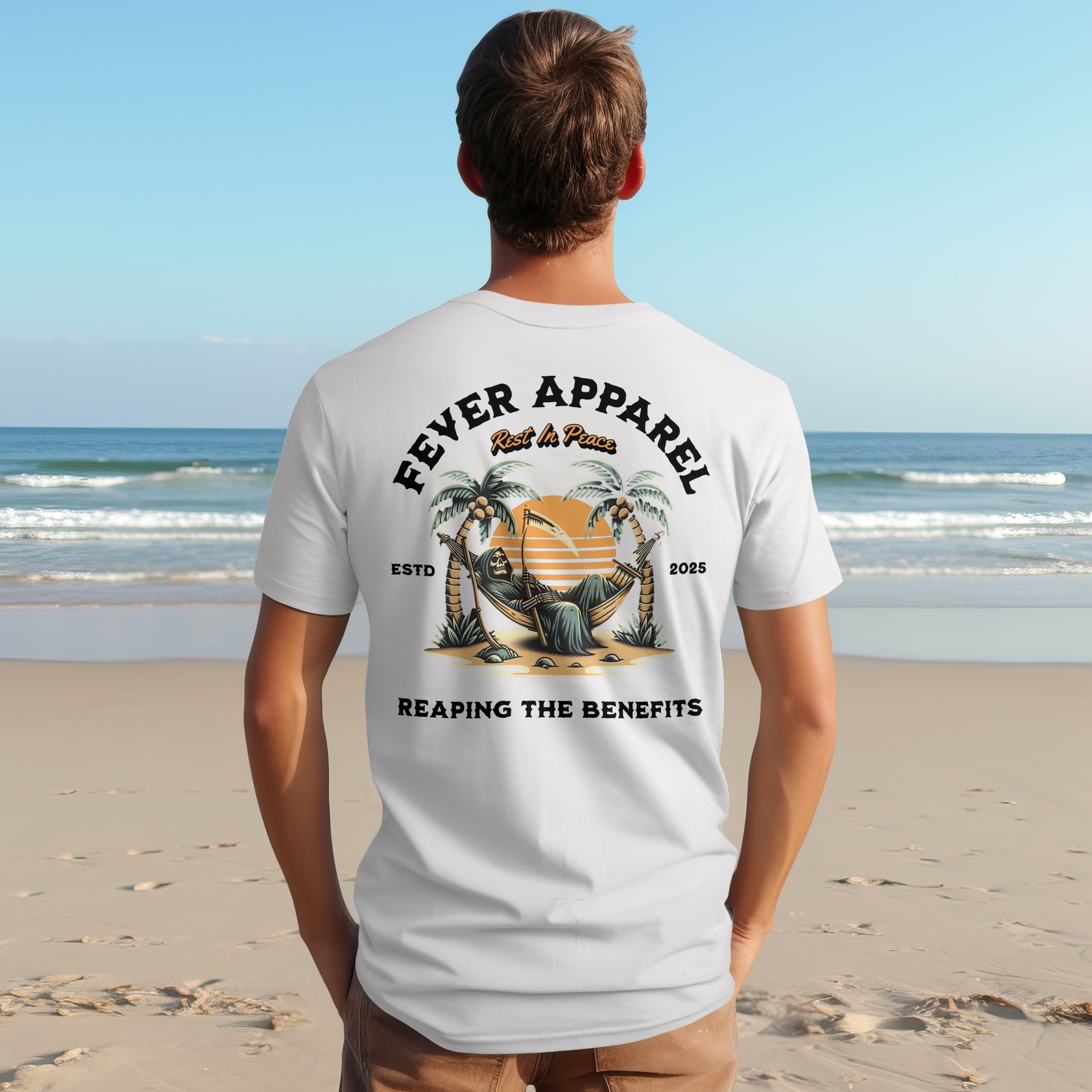 Back of a person wearing a white T-shirt with a beach-themed graphic design, standing on a sandy beach facing the ocean.