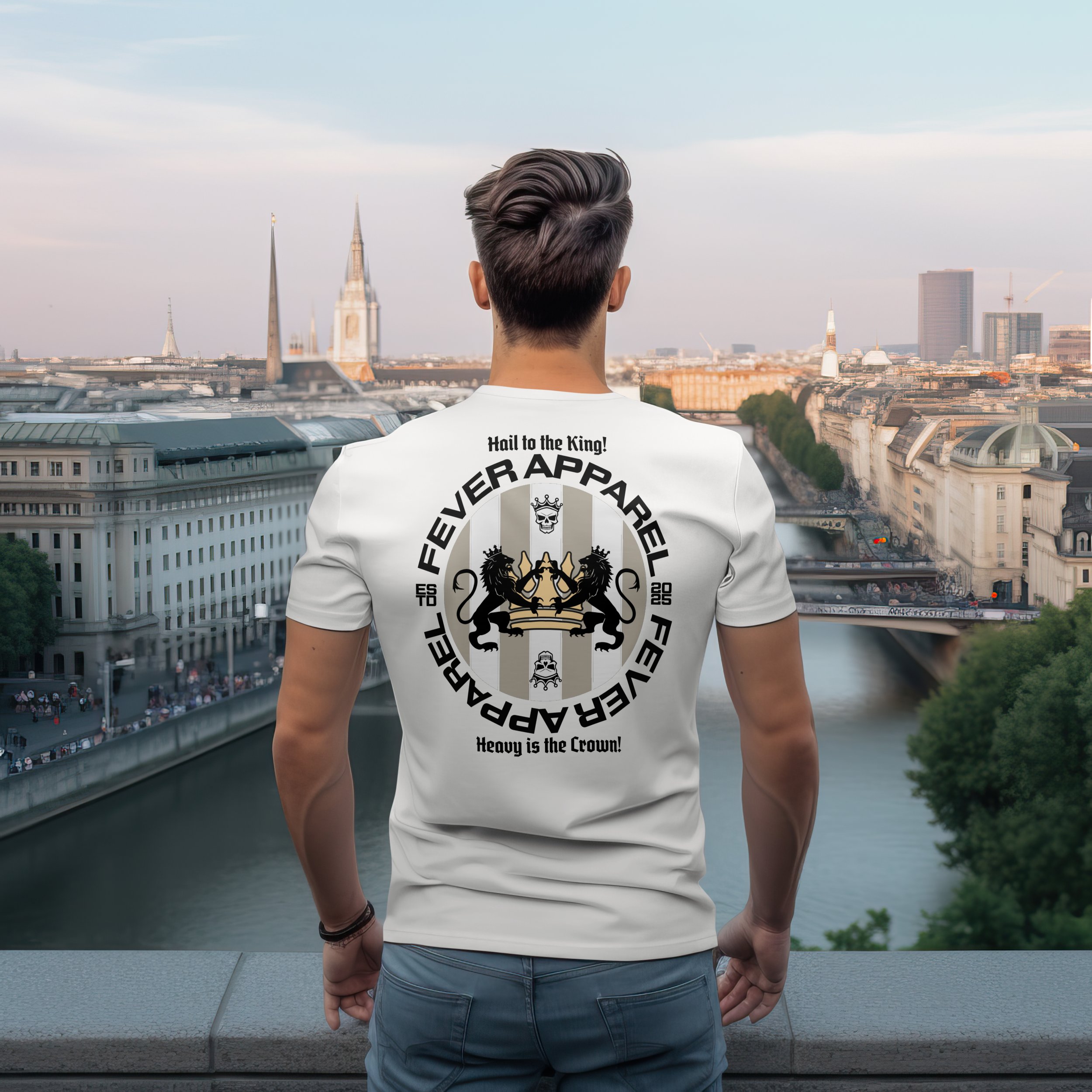 A young man with styled hair, wearing a white t-shirt with the Fever Apparel logo on the back, stands overlooking a city river and skyline.