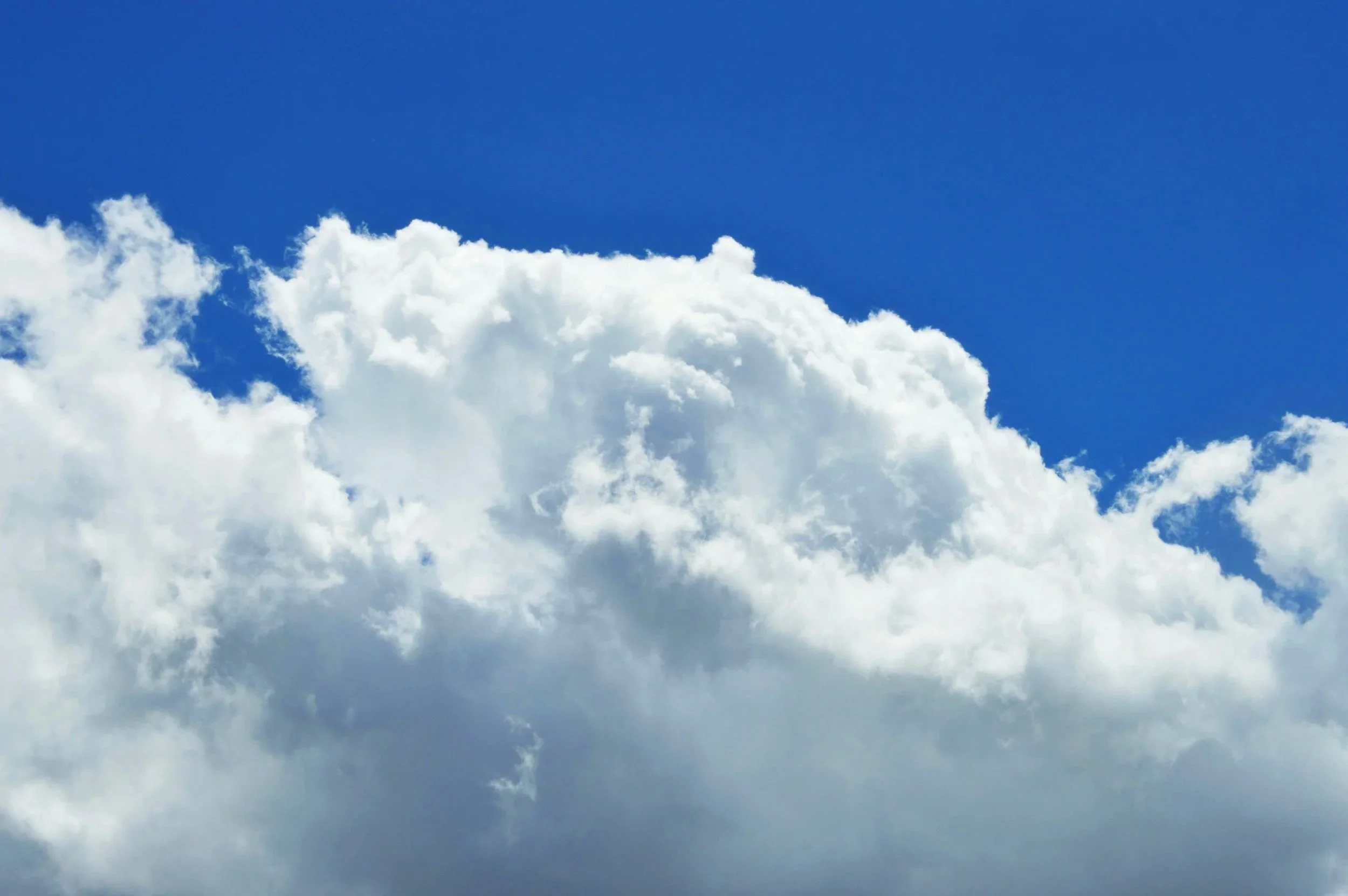 Bright blue sky with large white fluffy clouds.