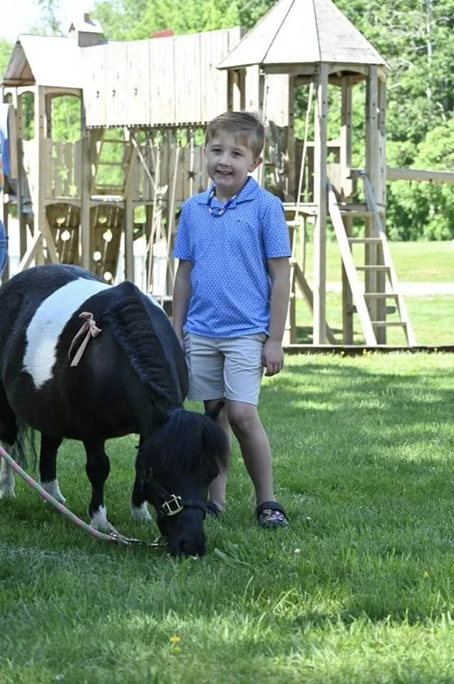 mini horse eating grass boy portrait.jpg