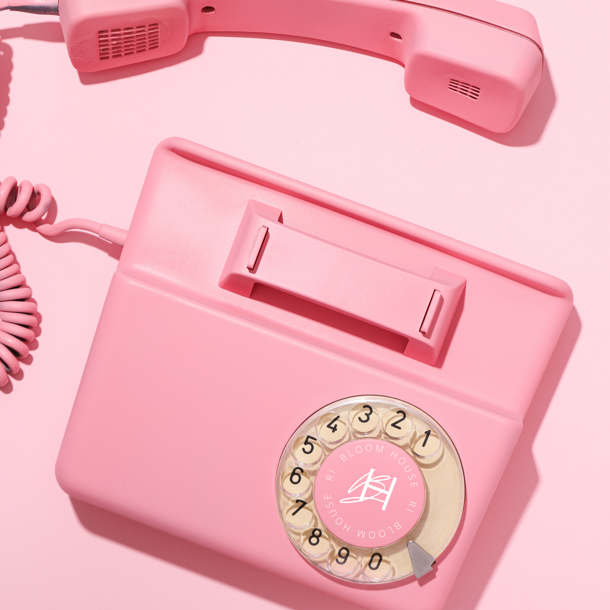Close-up of a vintage pink rotary phone on a pink background.