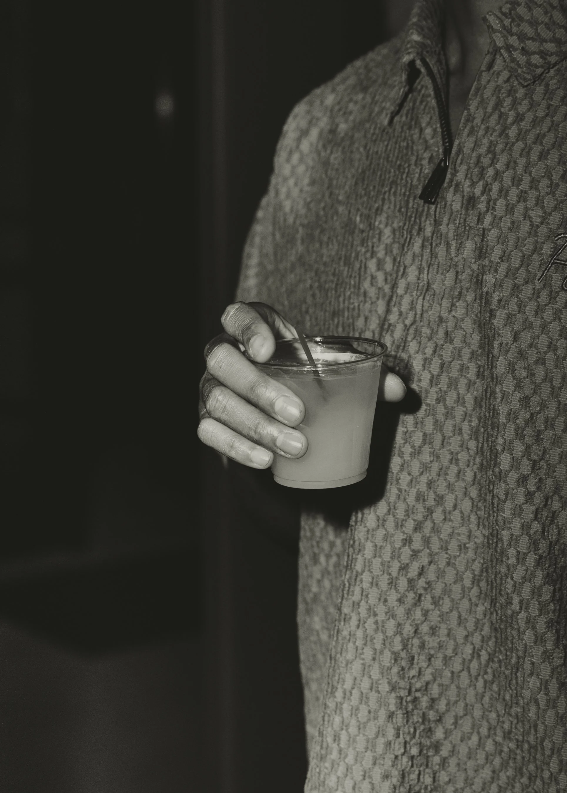 Person wearing textured sweater holding a glass of beverage in their hand.