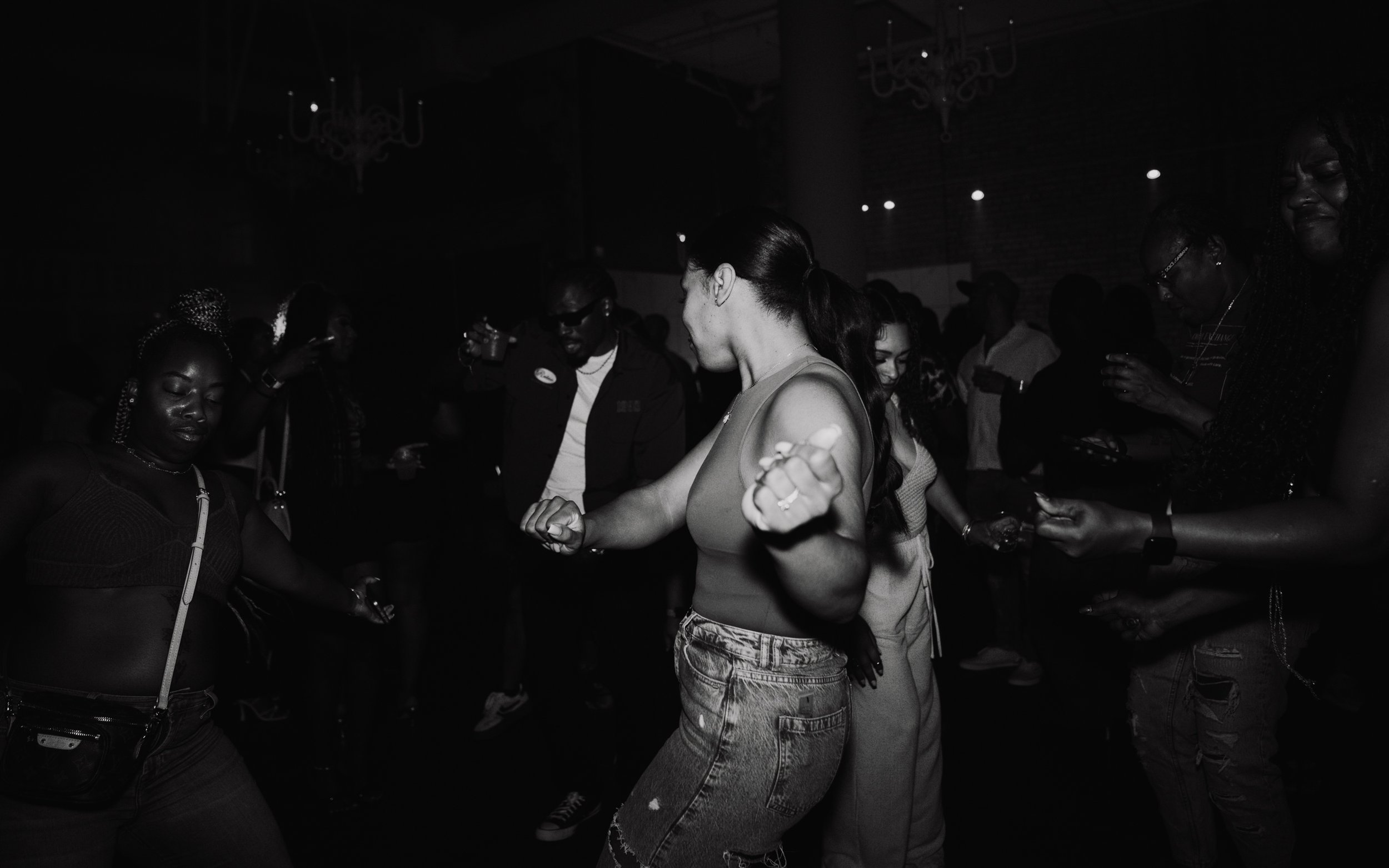People dancing and socializing in a dark nightclub or party setting.