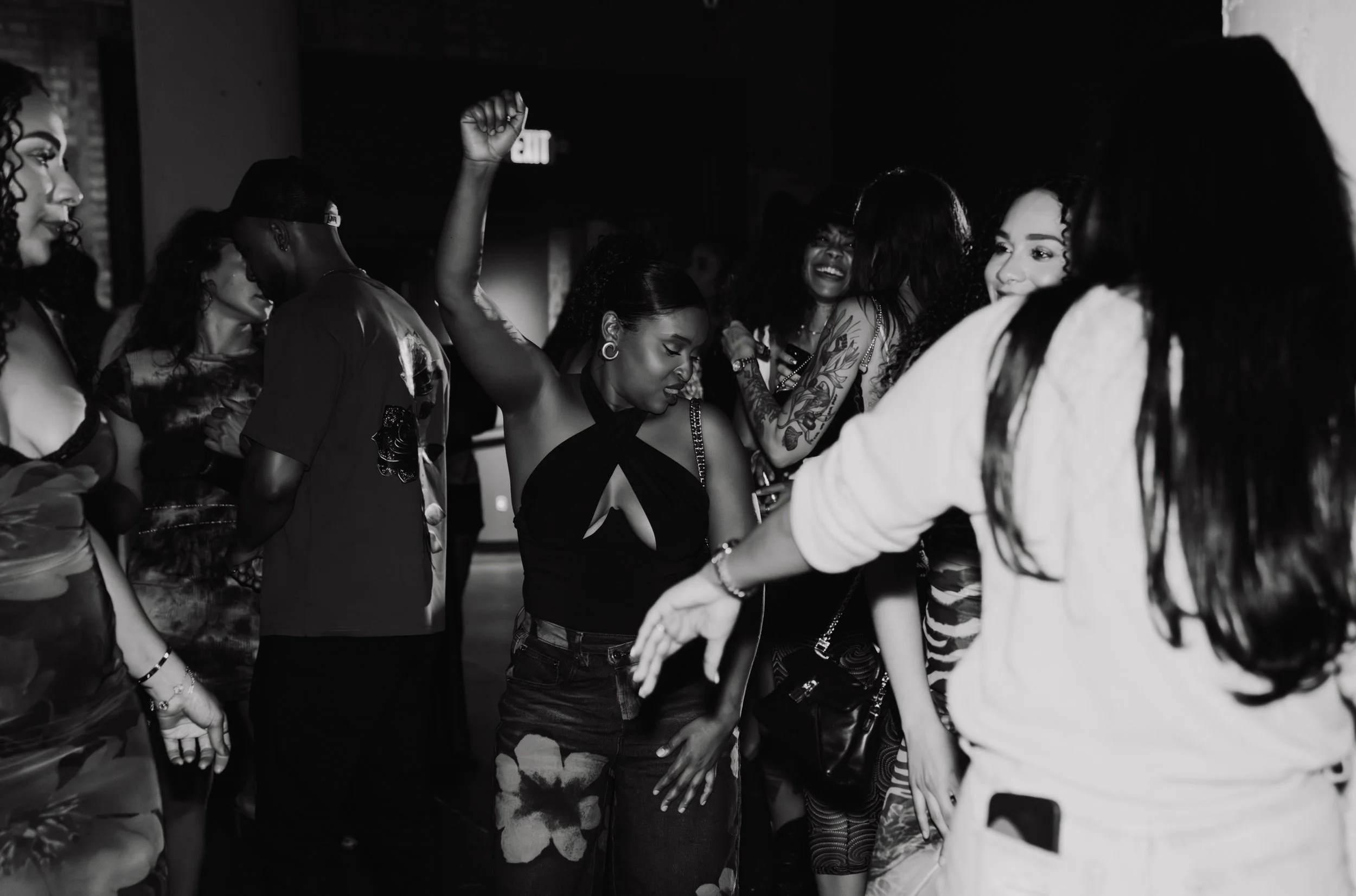 Group of diverse women dancing and enjoying music at a party or nightclub, smiling and having fun. Black and white photo.