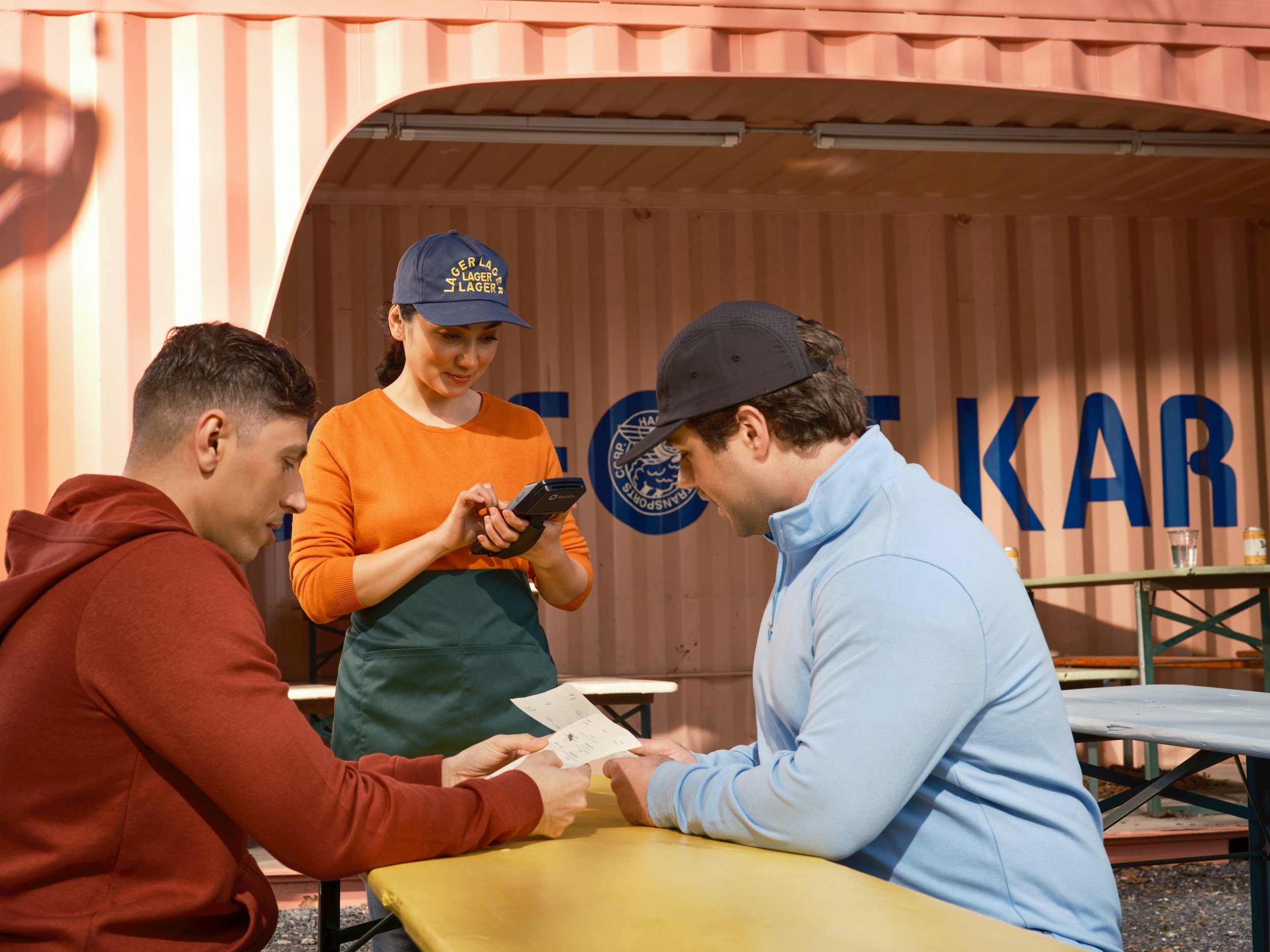 Outdoor restaurant customers being served in a branded commercial space featuring custom graphics.