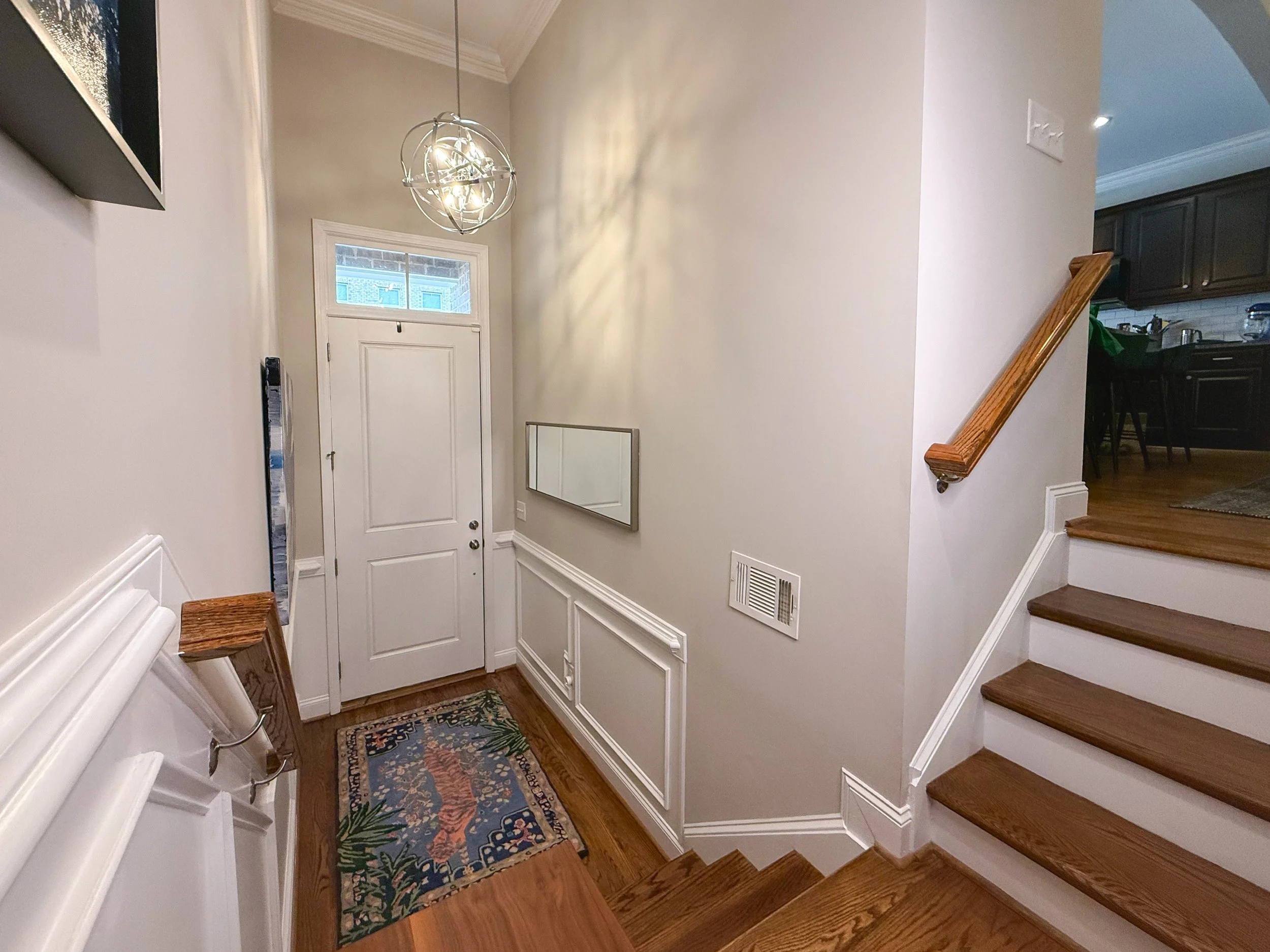 Welcoming foyer with soaring ceilings, modern sputnik light fixture, and elegant wall molding