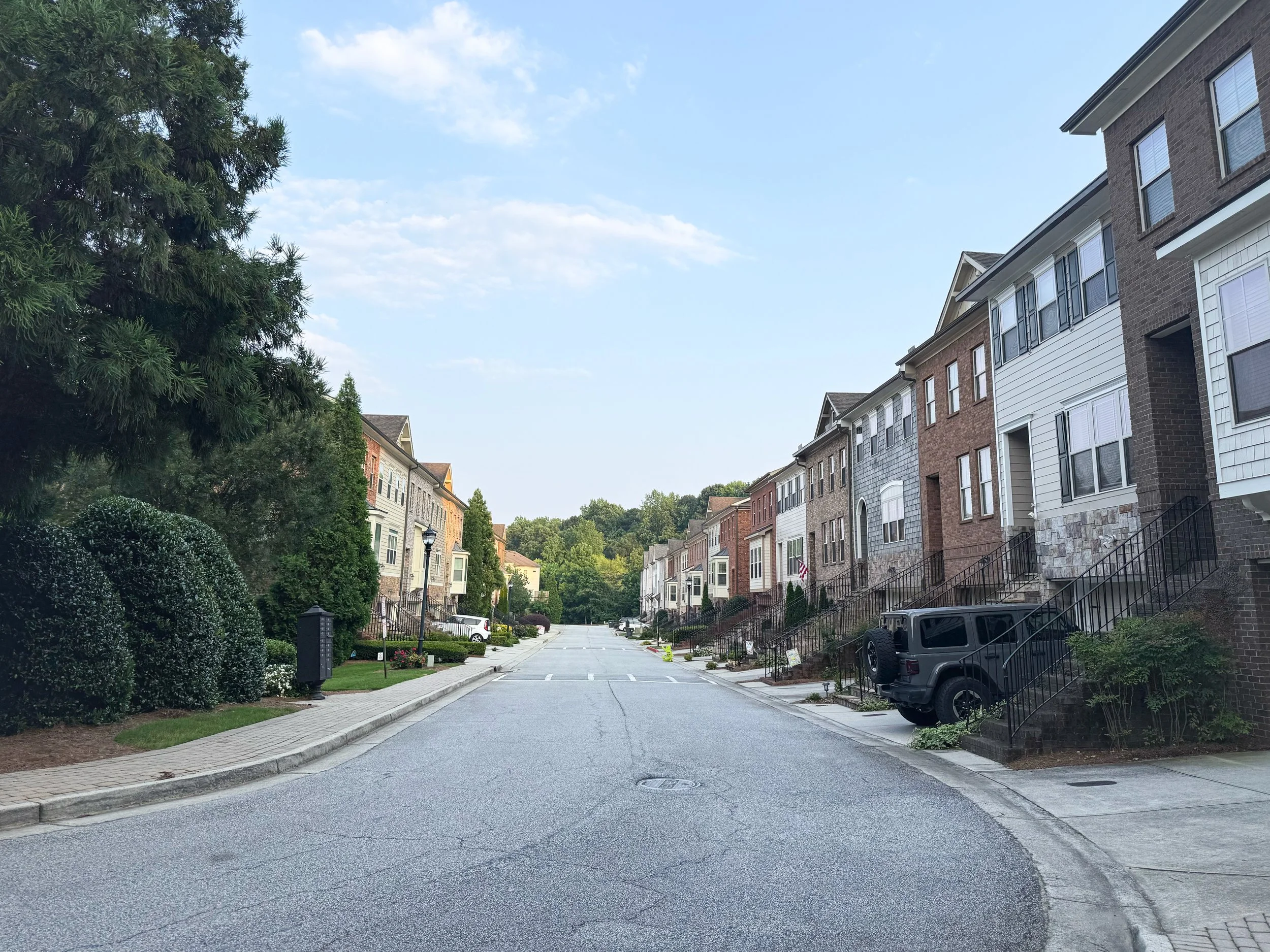 Wide, peaceful street lined with greenery—West Village Lane features unique townhomes with varied finishes for a non-cookie-cutter feel.
