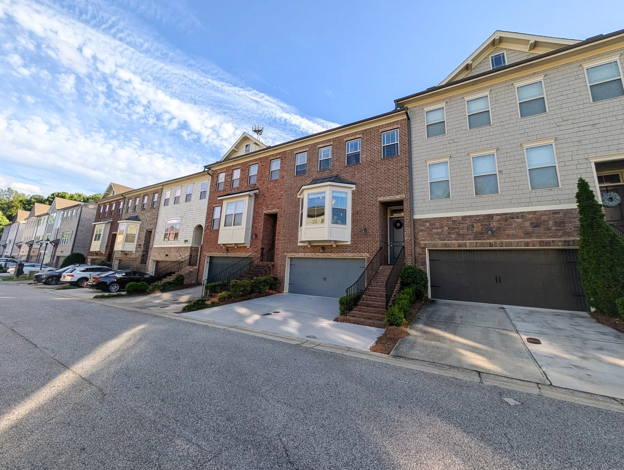 Brick-front townhome with two-car garage, spacious driveway, and abundant windows