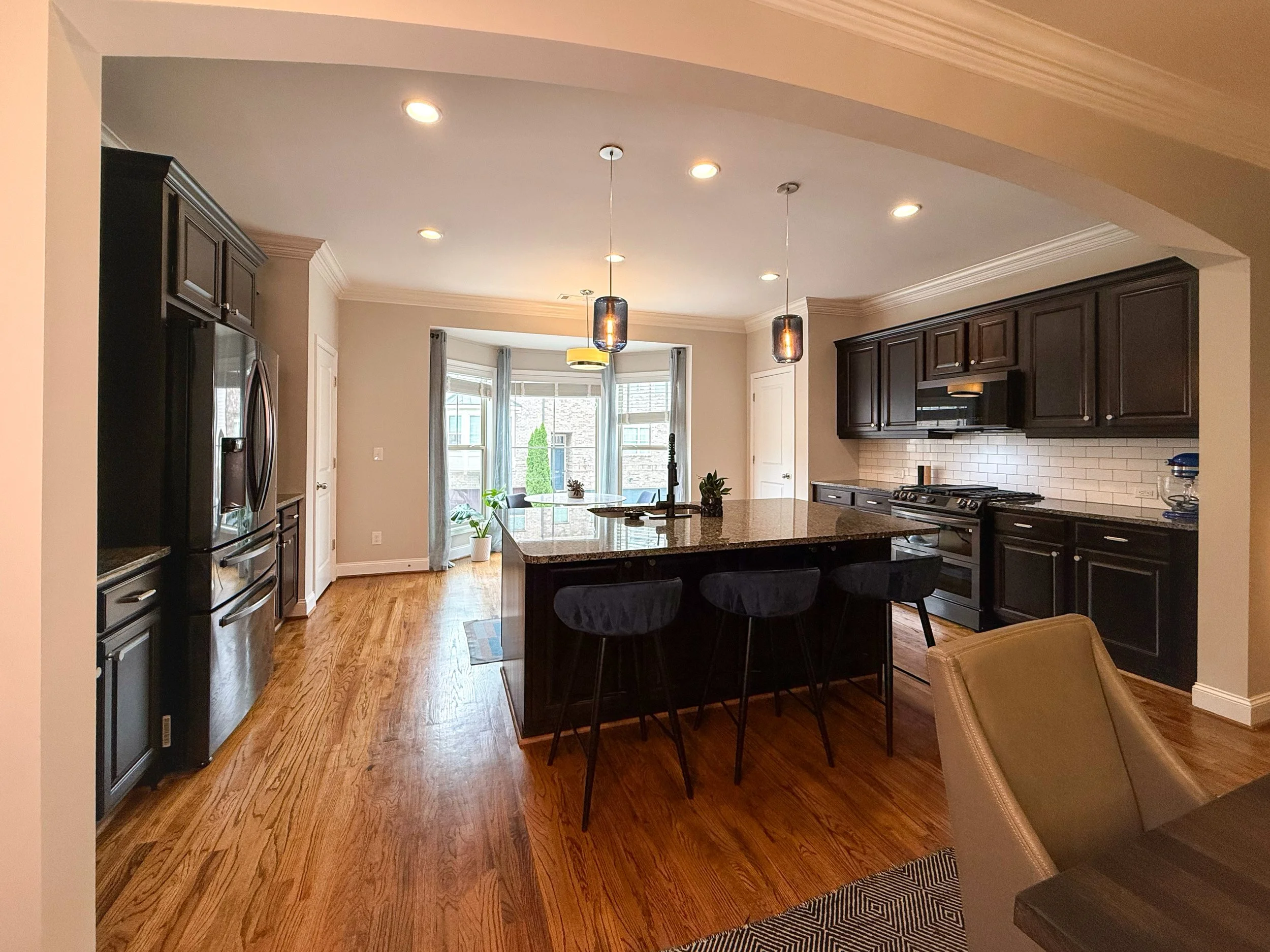 Spacious open-concept kitchen with wood cabinetry, black stainless appliances, granite countertops, and custom cabinet pull-outs