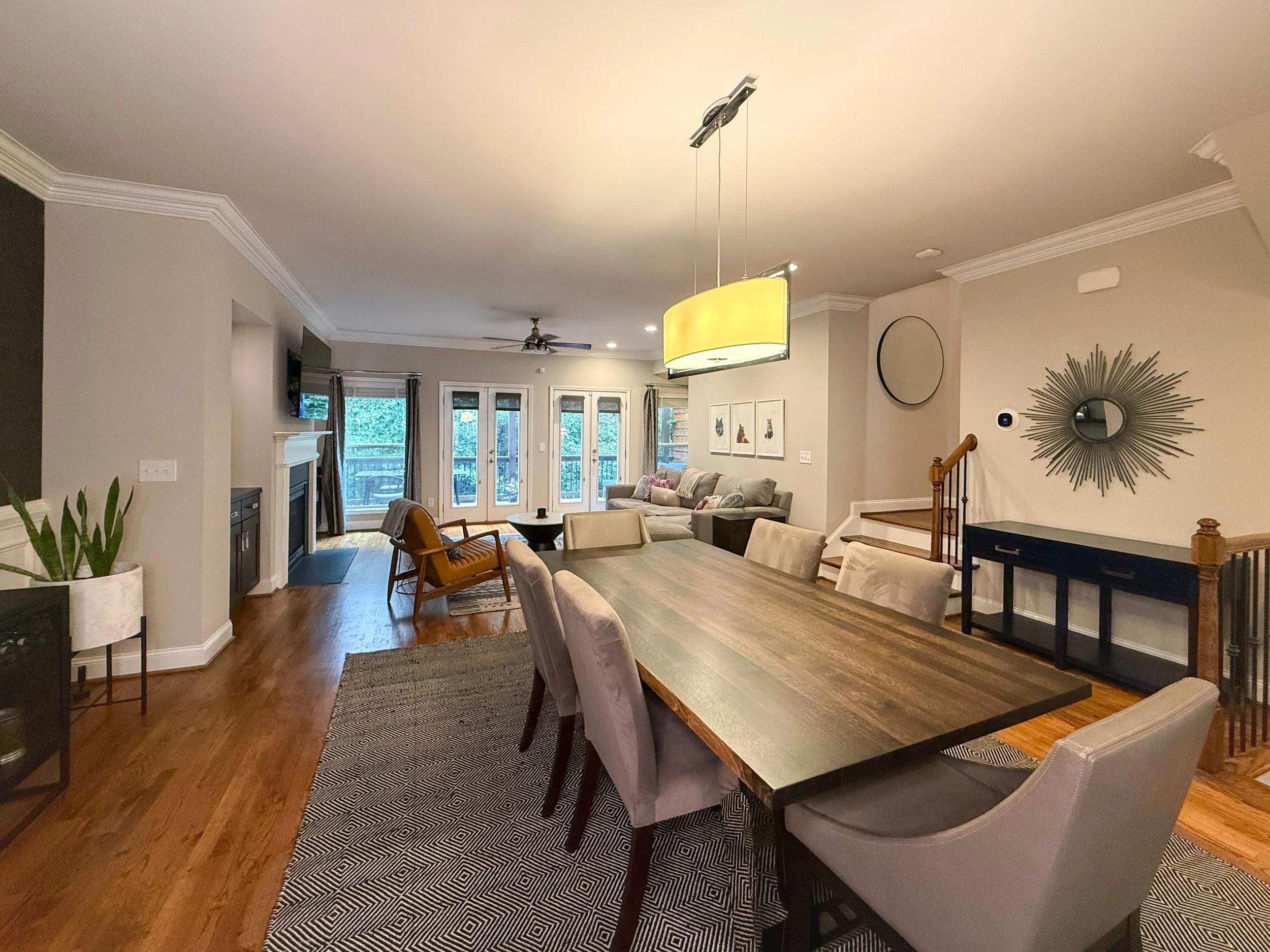 Open-concept dining area with designer lighting, modern grasscloth wallpaper, and space for a large table