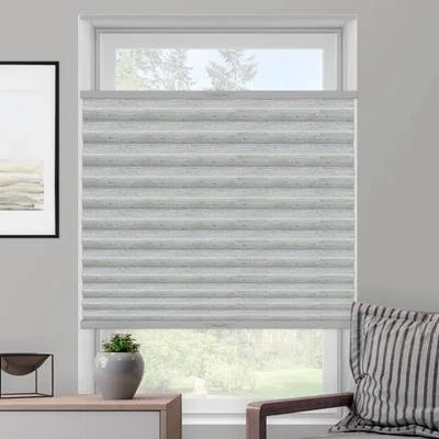 A window with a striped gray and white fabric Roman shade partially lowered, next to a gray and white striped pillow on a chair.