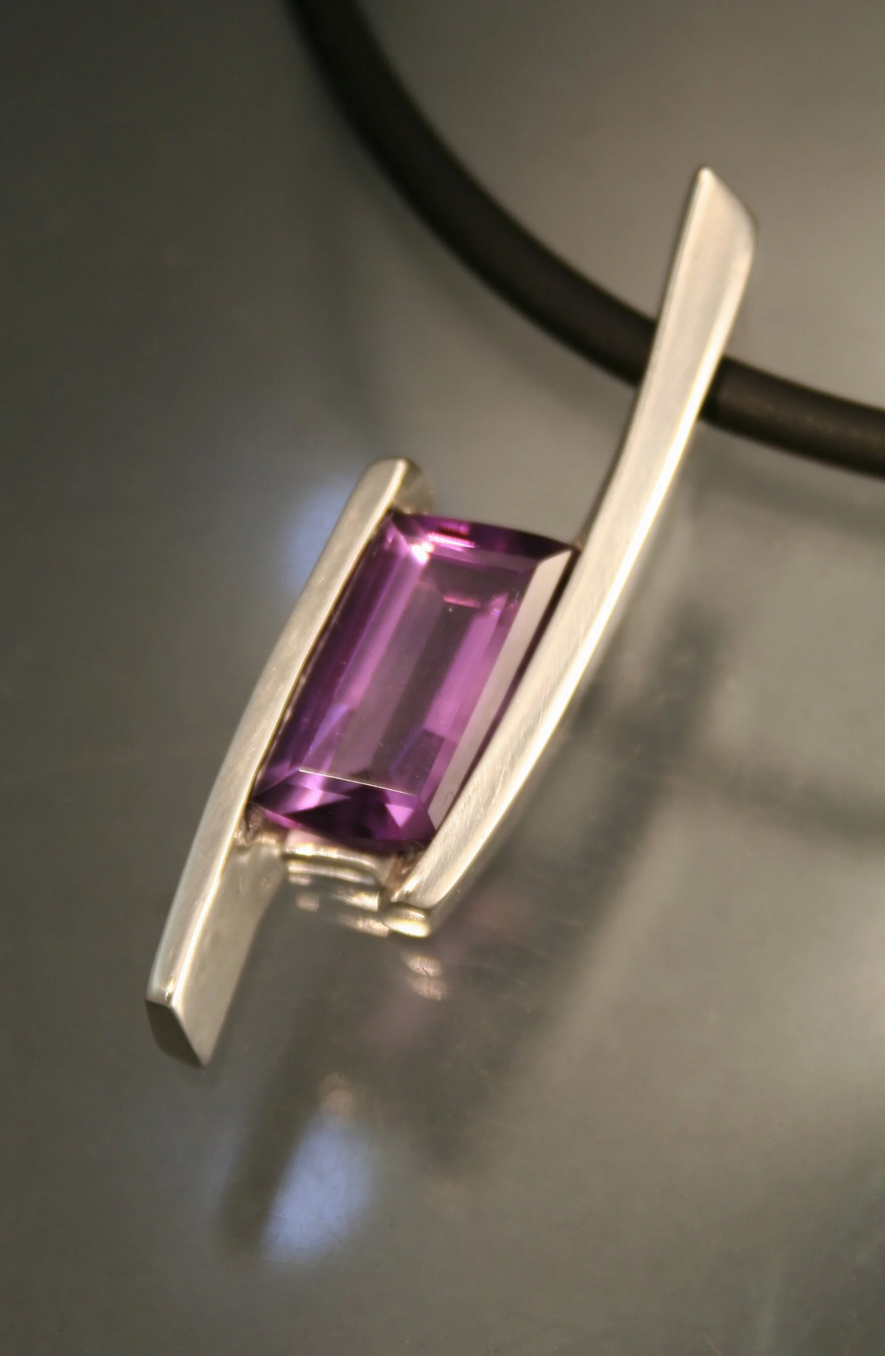 Silver ring with a rectangular purple gemstone.