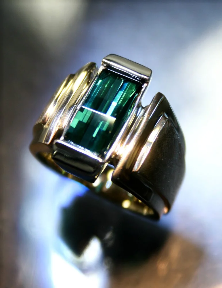 A silver ring with a large rectangular green gemstone set in the center.