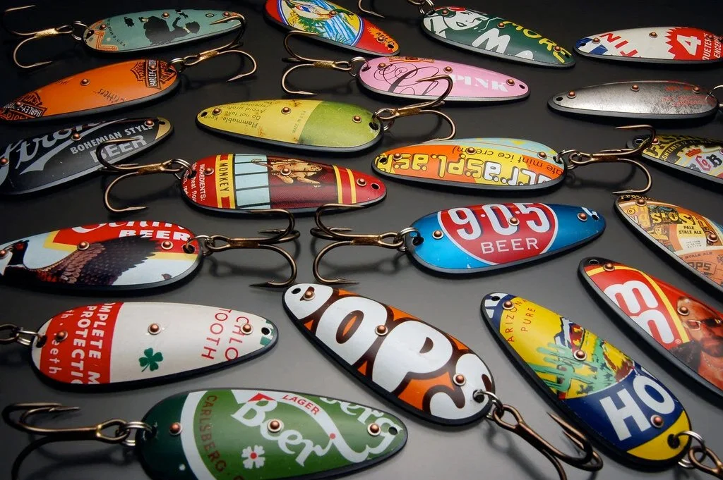 Collection of colorful fishing lures with various designs and branding, laid out on a surface.